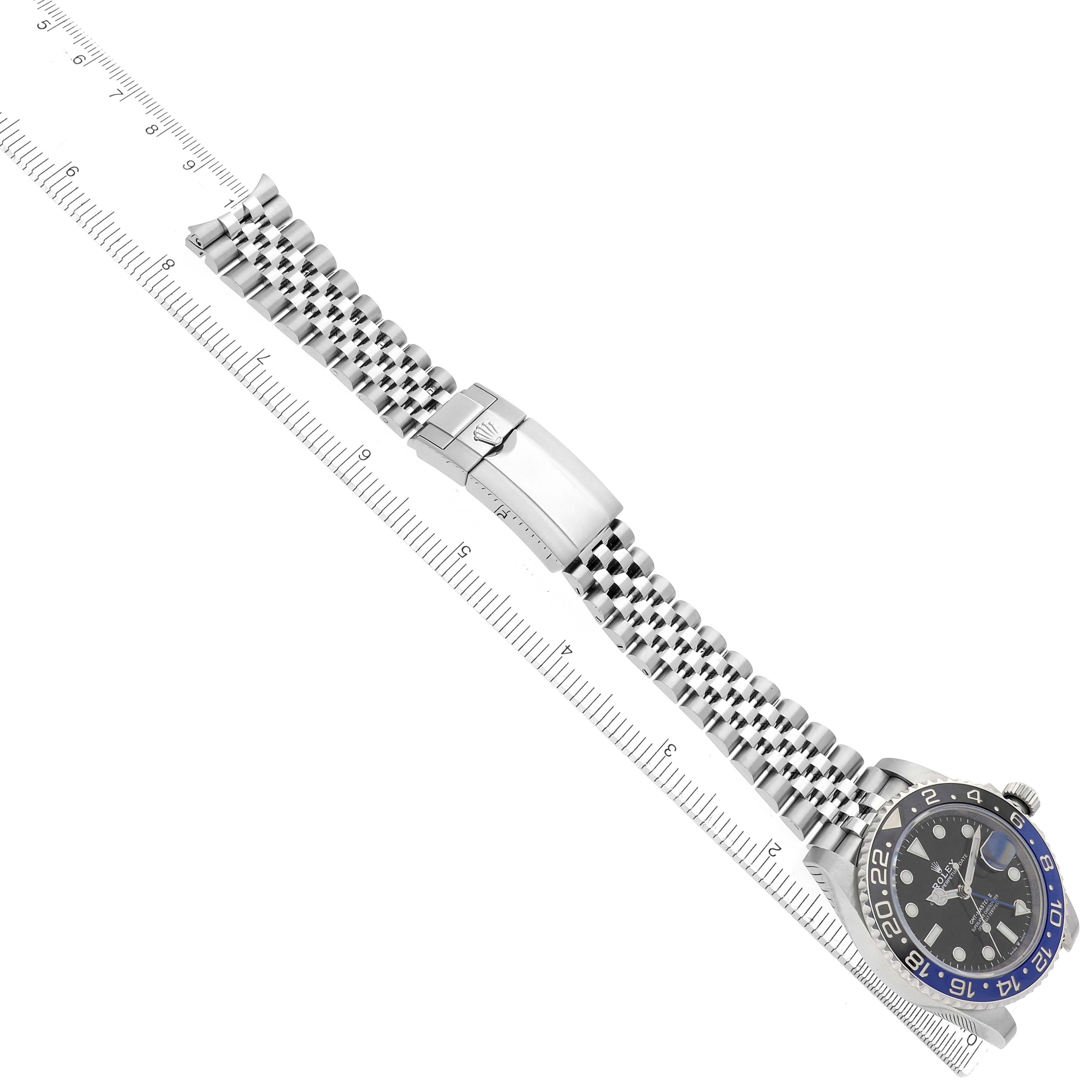 The Rolex GMT-Master model 126710 is shown at an overhead angle, displaying the face, bezel, bracelet, and clasp, aligned with a ruler for scale.