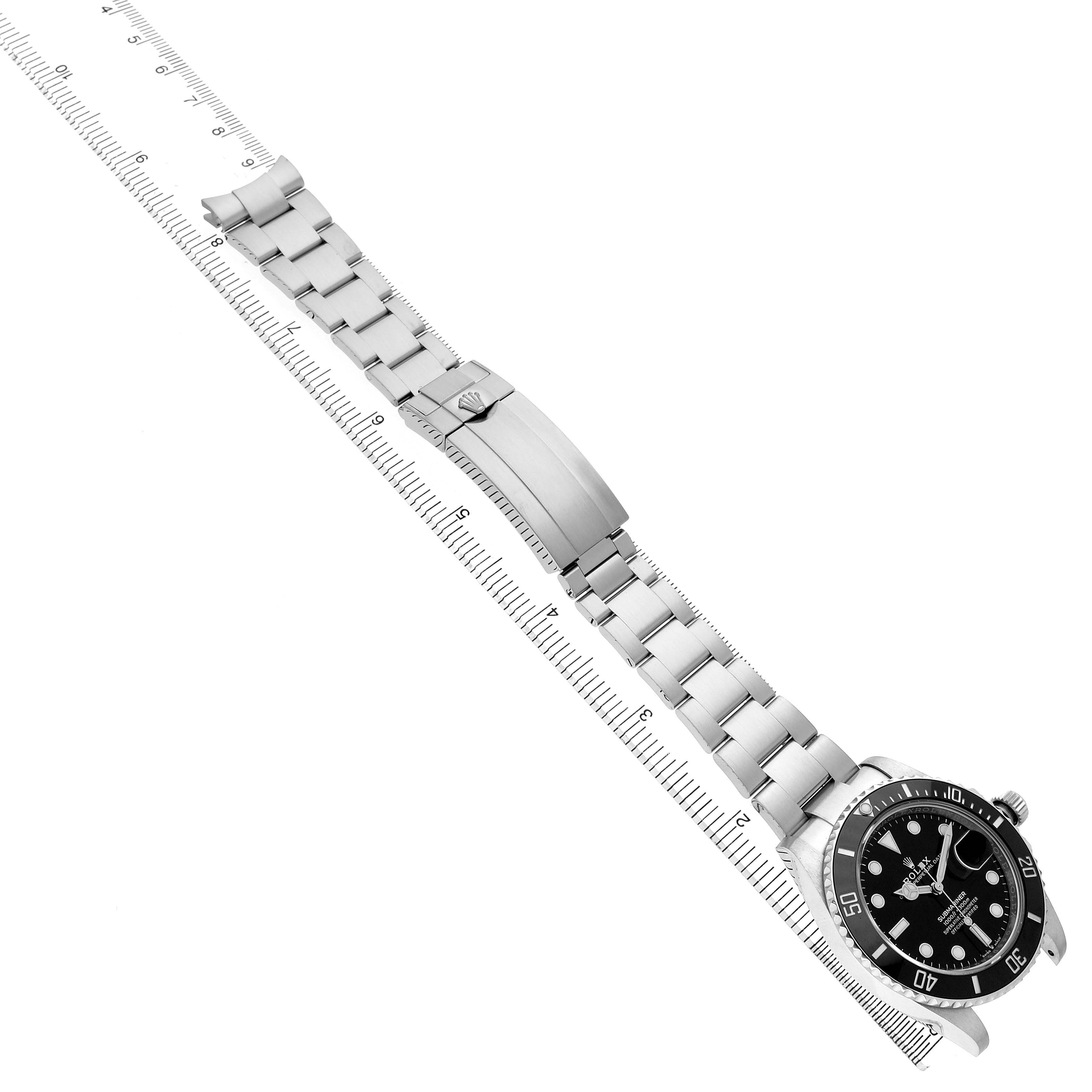 The Rolex Submariner 126610LN Men's Stainless Steel Black Dial watch is shown at an angle, displaying the full bracelet, clasp, and dial alongside a ruler for scale.
