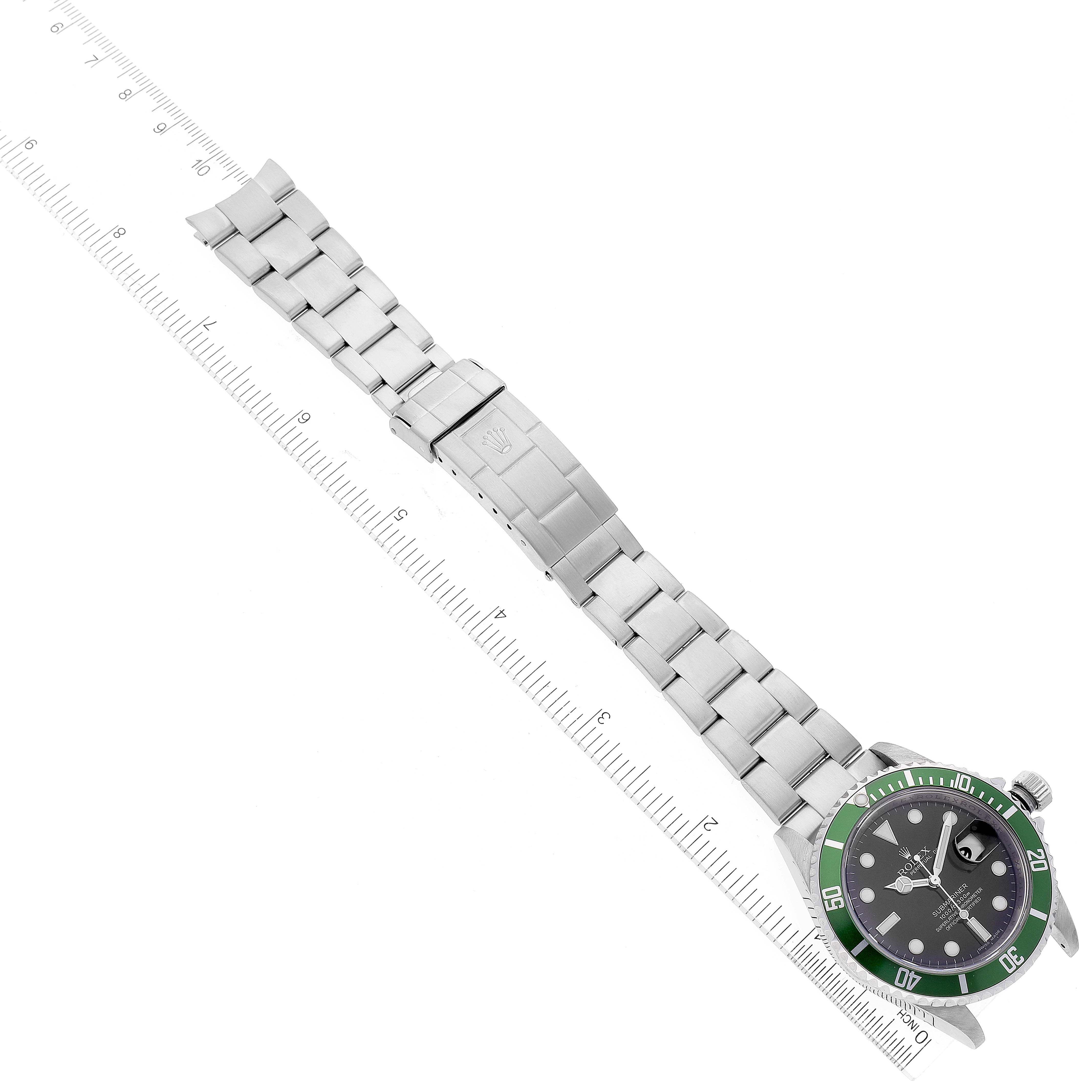 The image shows a Rolex Submariner 16610LV Men's Stainless Steel Black Dial 16610LV Men's Stainless Steel Black Dial watch laid out flat alongside a ruler, displaying its face, bezel, and stainless steel bracelet.