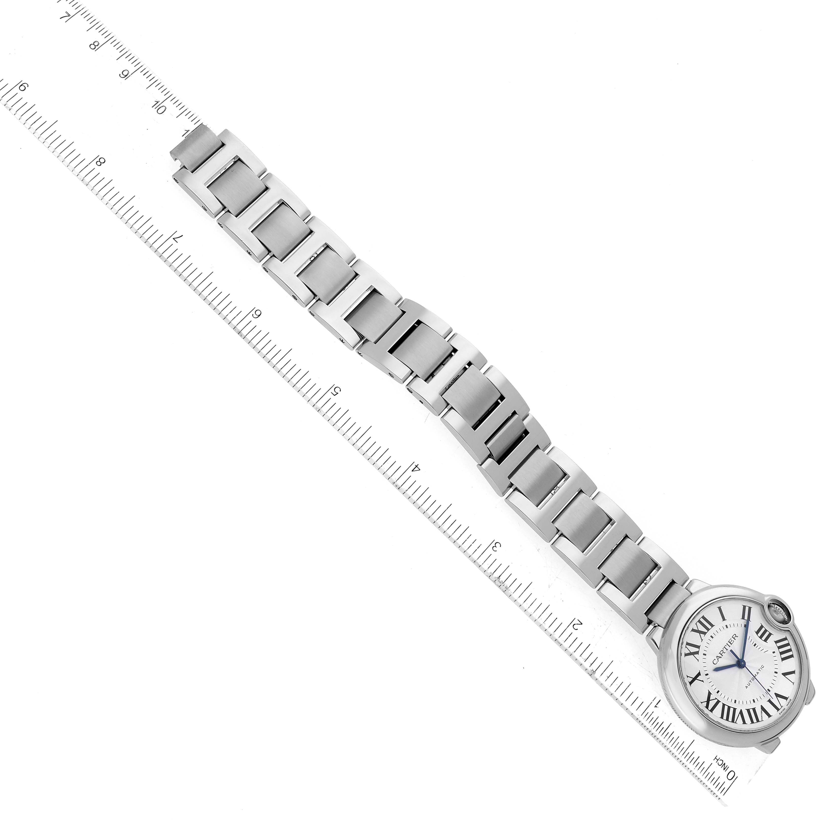 The image shows a Cartier Ballon Bleu W6920046 Women
s Stainless Steel Silver Dial W6920046 Women
s Stainless Steel Silver Dial model watch laid flat beside a ruler, displaying the bracelet and the dial face.