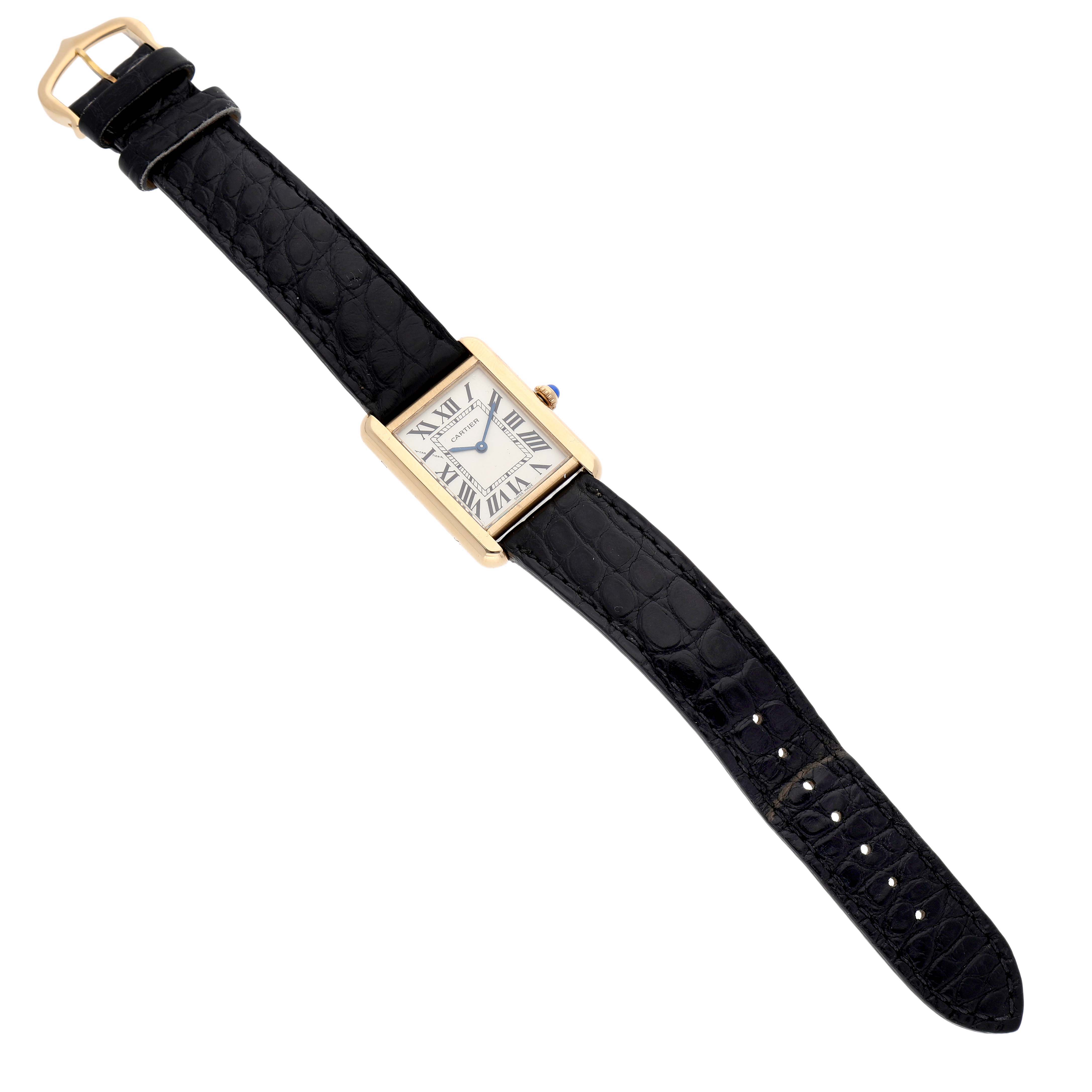 The Cartier Tank Solo W1018755 Women's Yellow Gold Silver Dial watch is shown from an overhead angle, displaying its face, strap, and clasp.