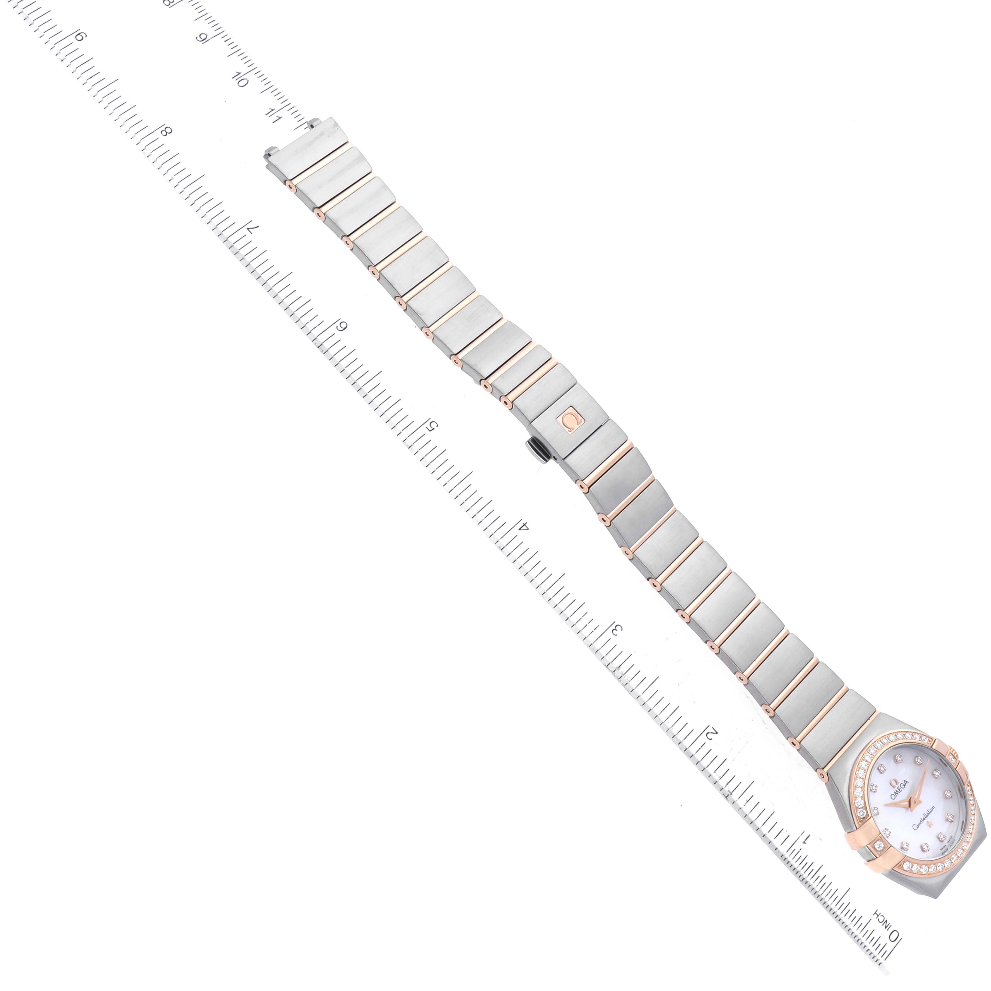 The image shows an Omega 123.25.27.60.55.001 Women's Steel and Gold (two tone) Mother of Pearl Dial 123.25.27.60.55.001 Women's Steel and Gold (two tone) Mother of Pearl Dial Constellation Steel Rose Gold Mother of Pearl Diamond Dial Ladies Watch 123.25.27.60.55.001 laid out flat with a ruler.