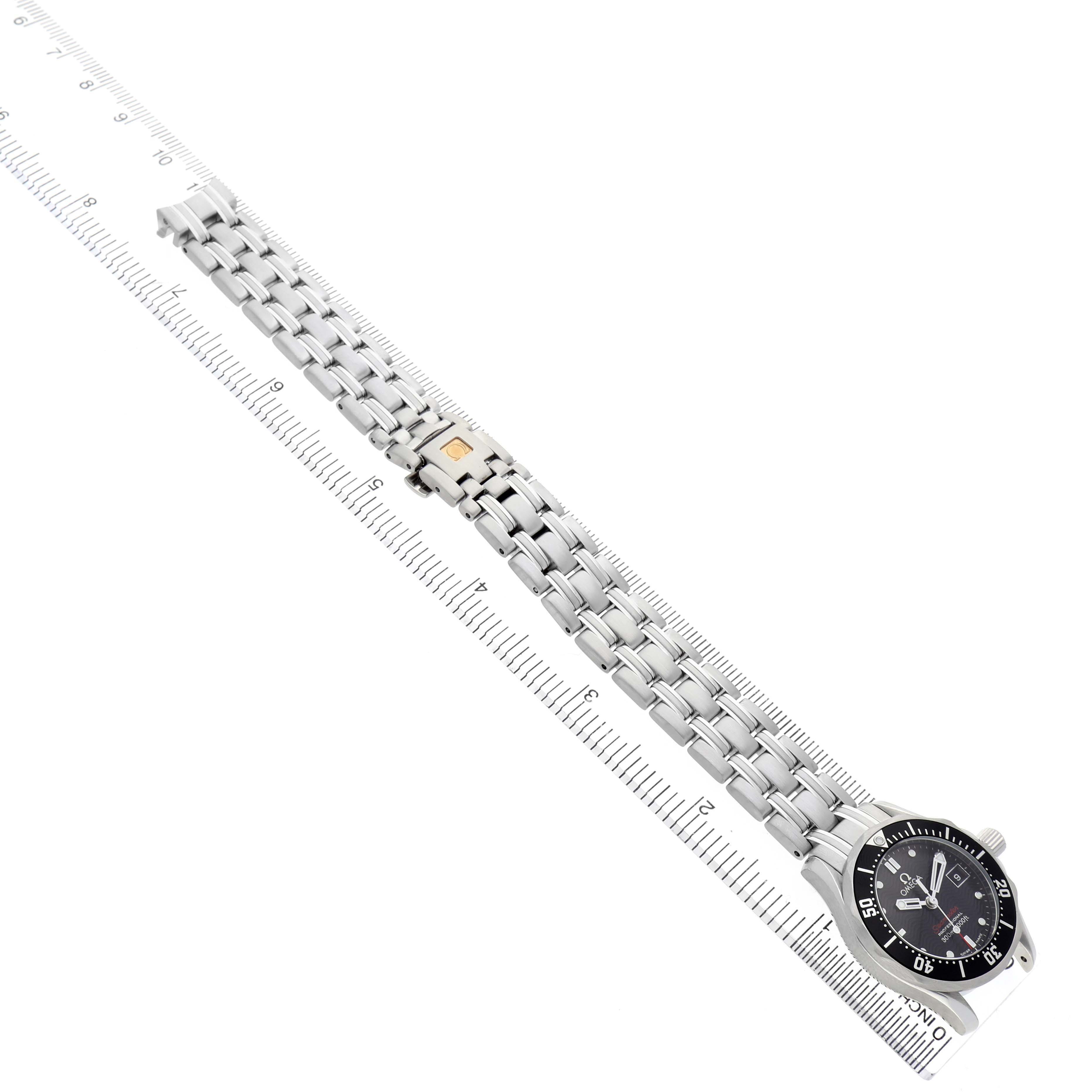 The Omega 212.30.28.61.01.001 Women's Stainless Steel Black Dial Seamaster Diver 300M watch is shown at an angle, highlighting the full bracelet and face alongside a measuring ruler.