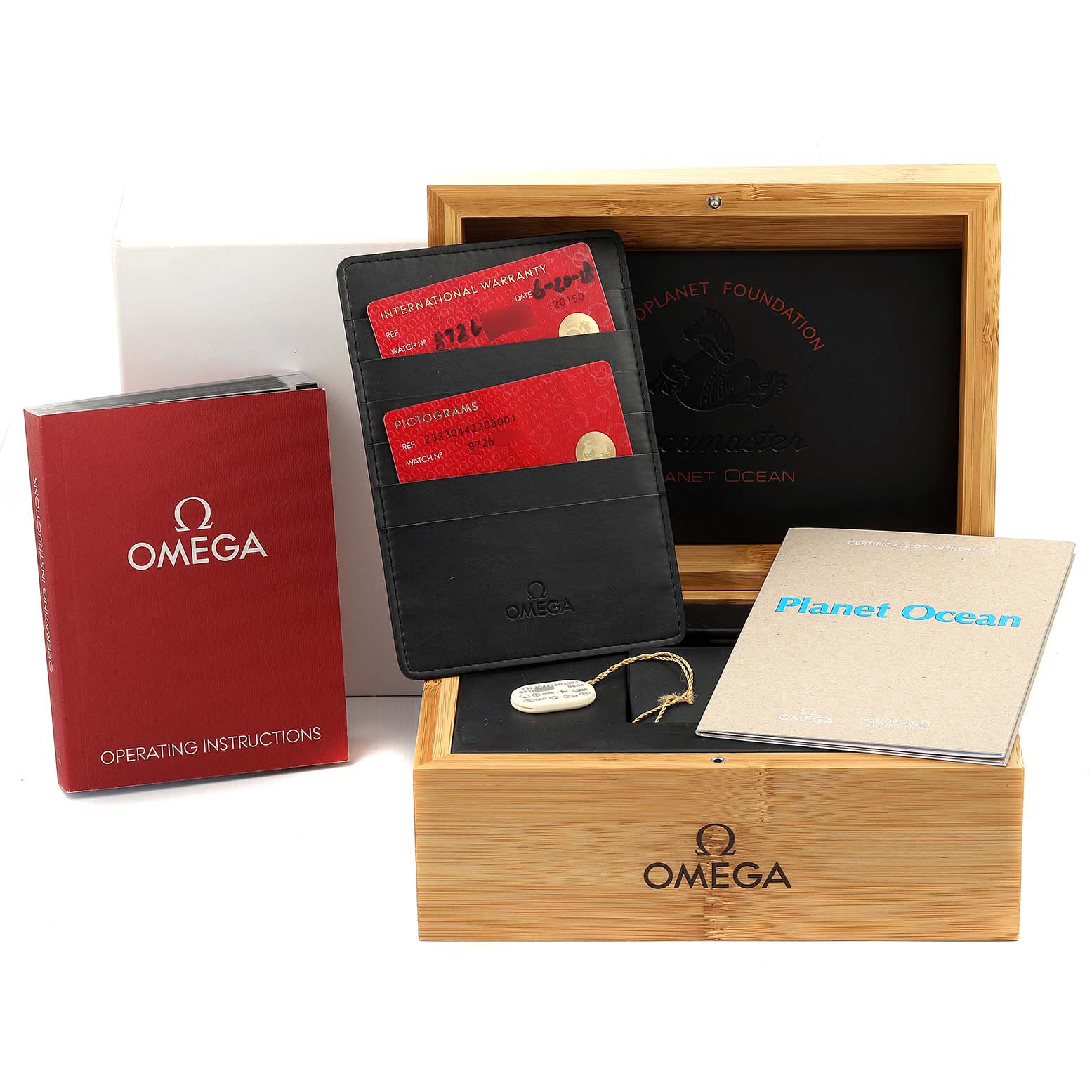 The image shows a Planet Ocean model by Omega with its box, warranty cards, operating instructions, and booklet from a direct front view.
