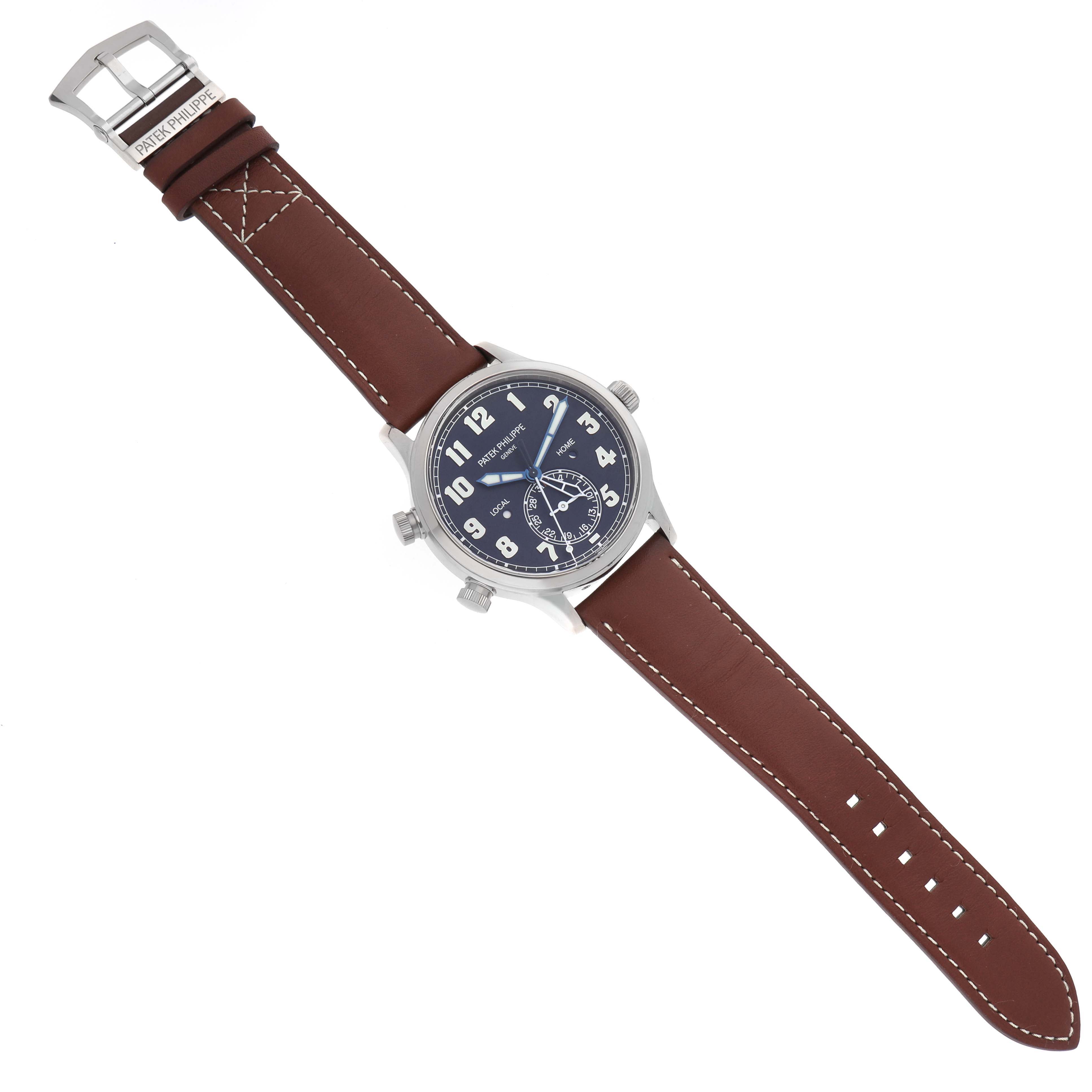 The Patek Philippe Calatrava model 5524G-001 is shown from a top-down angle, featuring its brown leather strap, blue dial, and silver case with visible crown and pushers.