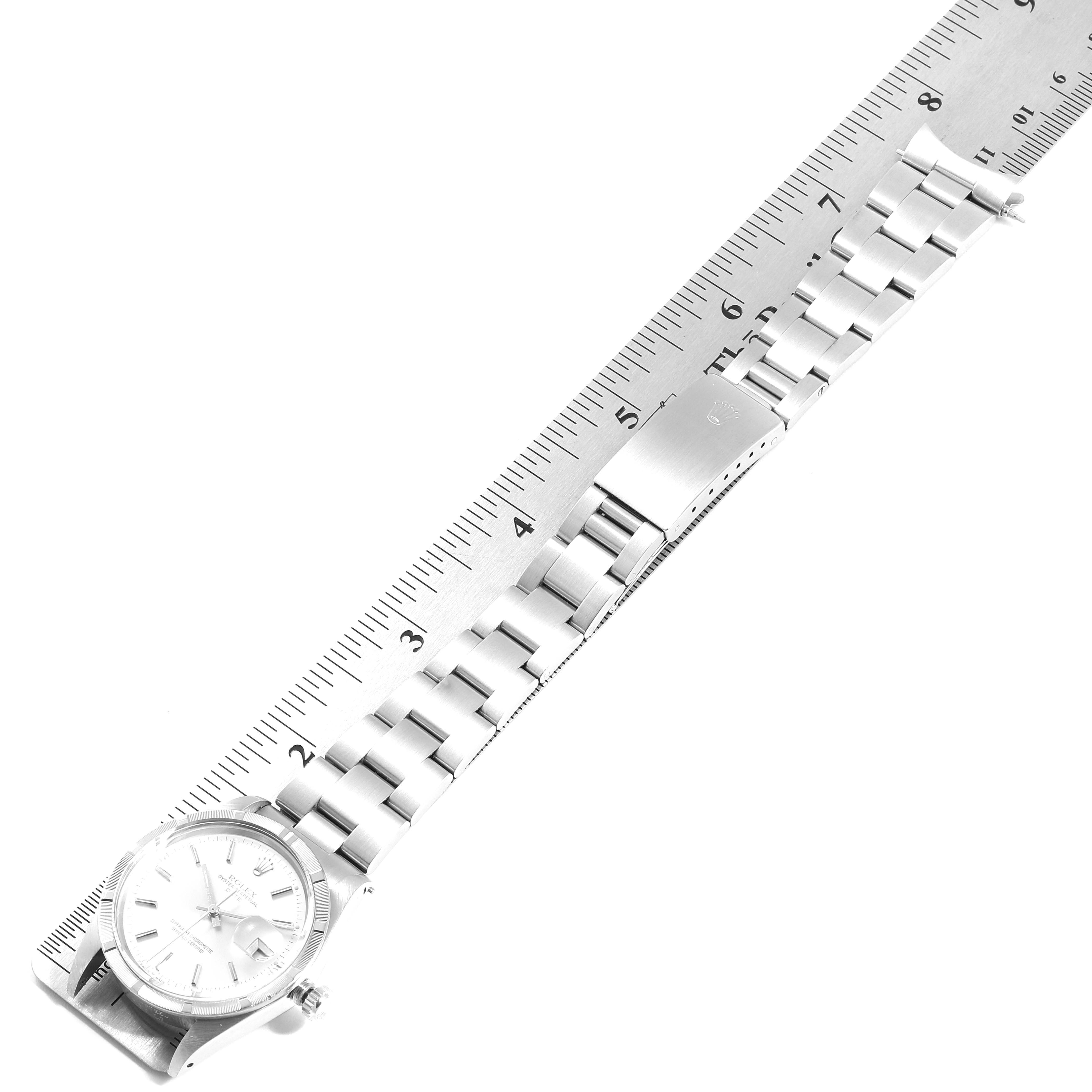 This image shows the full length of a Rolex Date 15010 Men's Stainless Steel Silver Dial 15010 Men's Stainless Steel Silver Dial watch laid flat with a ruler for scale.
