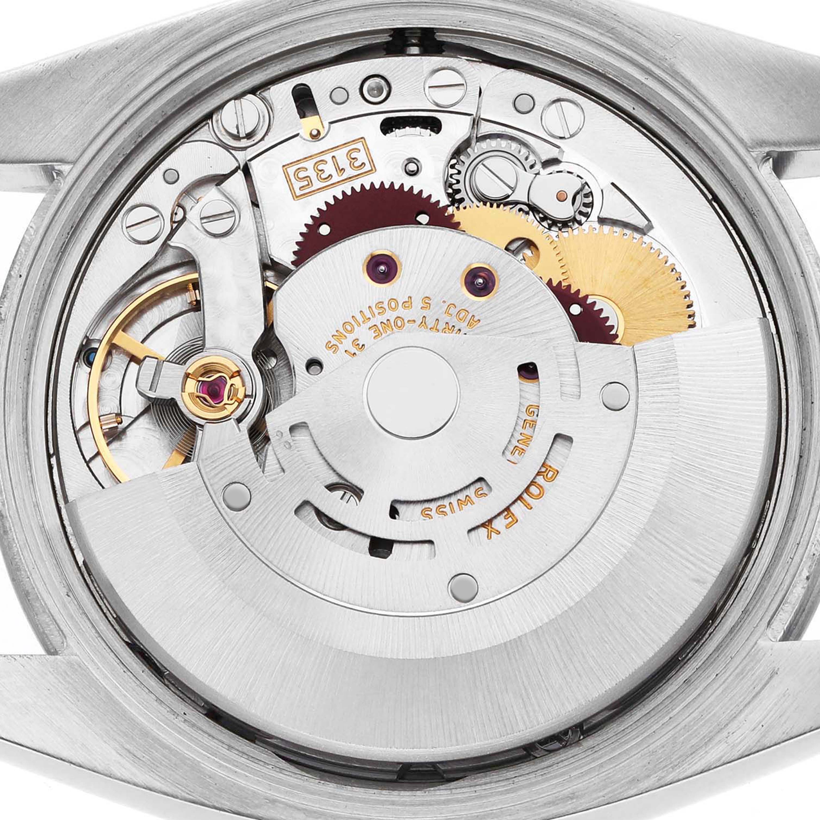 This image shows the internal mechanism of a Rolex Date 115210 Men's Stainless Steel White Dial model watch from a back angle, highlighting gears and movement components.