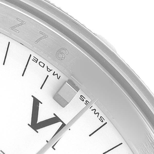 The image shows a close-up of the Rolex Date 115210 Men's Stainless Steel White Dial model, highlighting the edge of the watch face and part of the bezel.