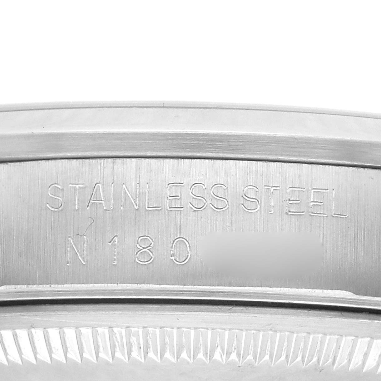 The image shows a close-up of the side of a Rolex Date model 15200, featuring the stainless steel engraving and part of the watch's fluted bezel.