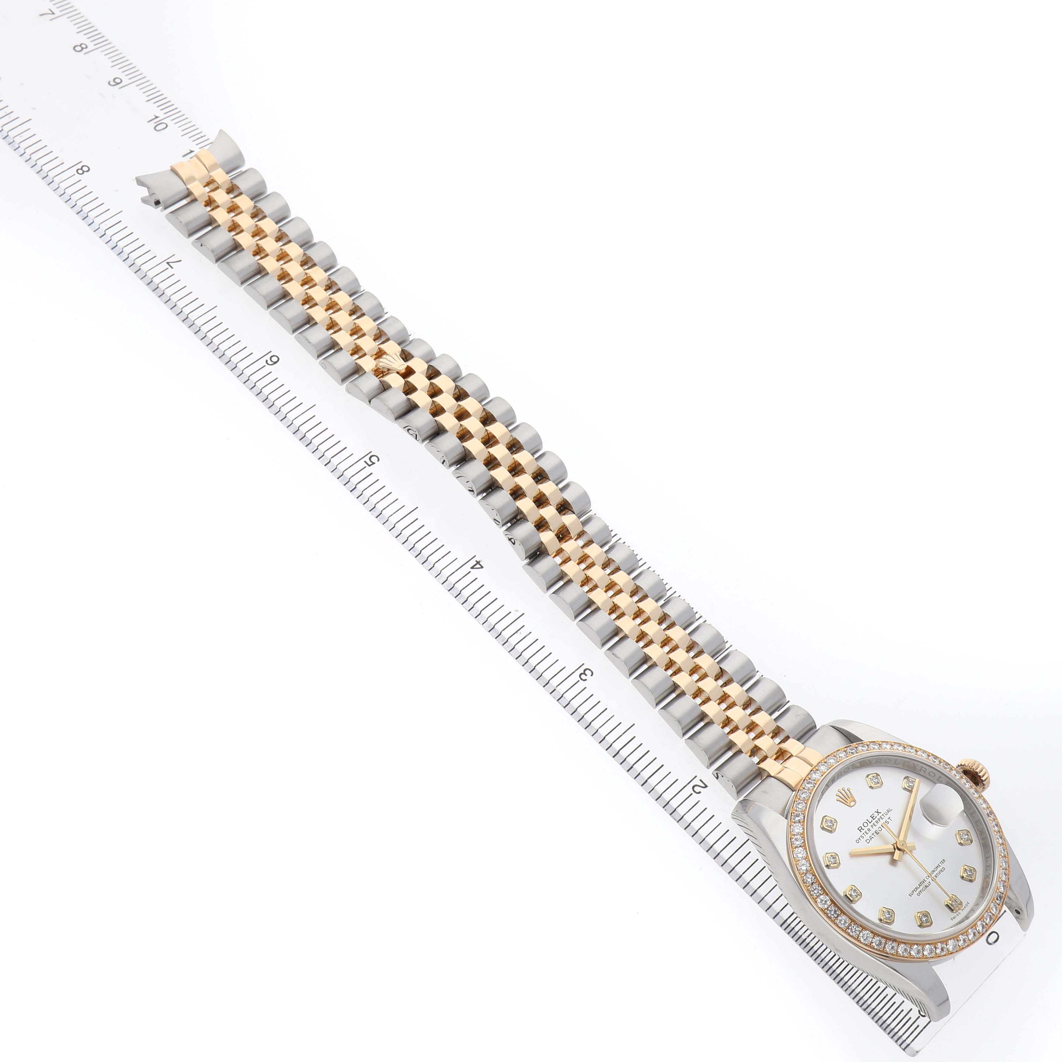 The Rolex Datejust 116243 Men's Stainless Steel Silver Dial is shown from a top-down angle, highlighting the full bracelet, bezel, and watch face next to a ruler for scale.