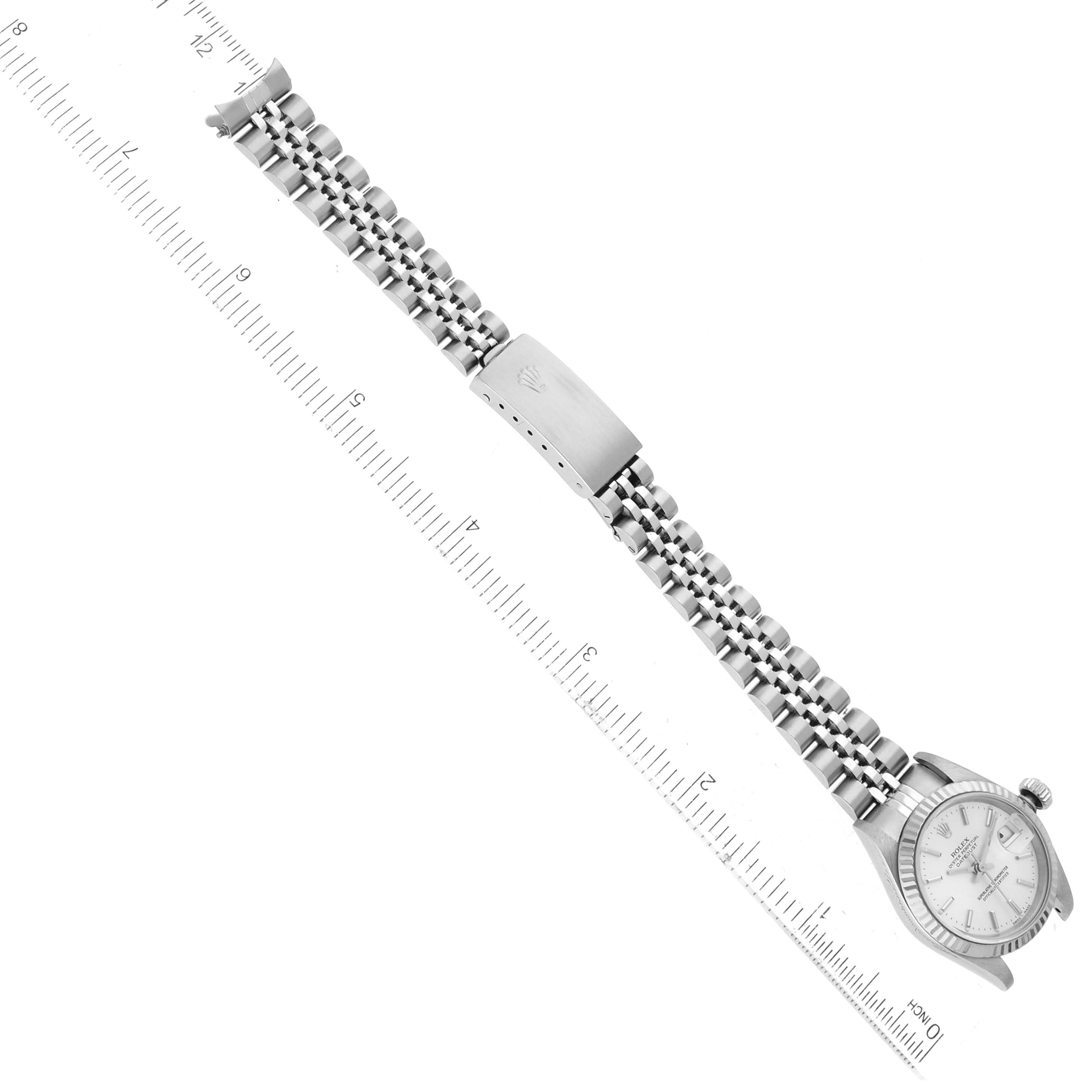 This image shows a Rolex Datejust 79174 Women's Stainless Steel Silver Dial 79174 Women's Stainless Steel Silver Dial watch laid flat with its bracelet extended and measured by a ruler.