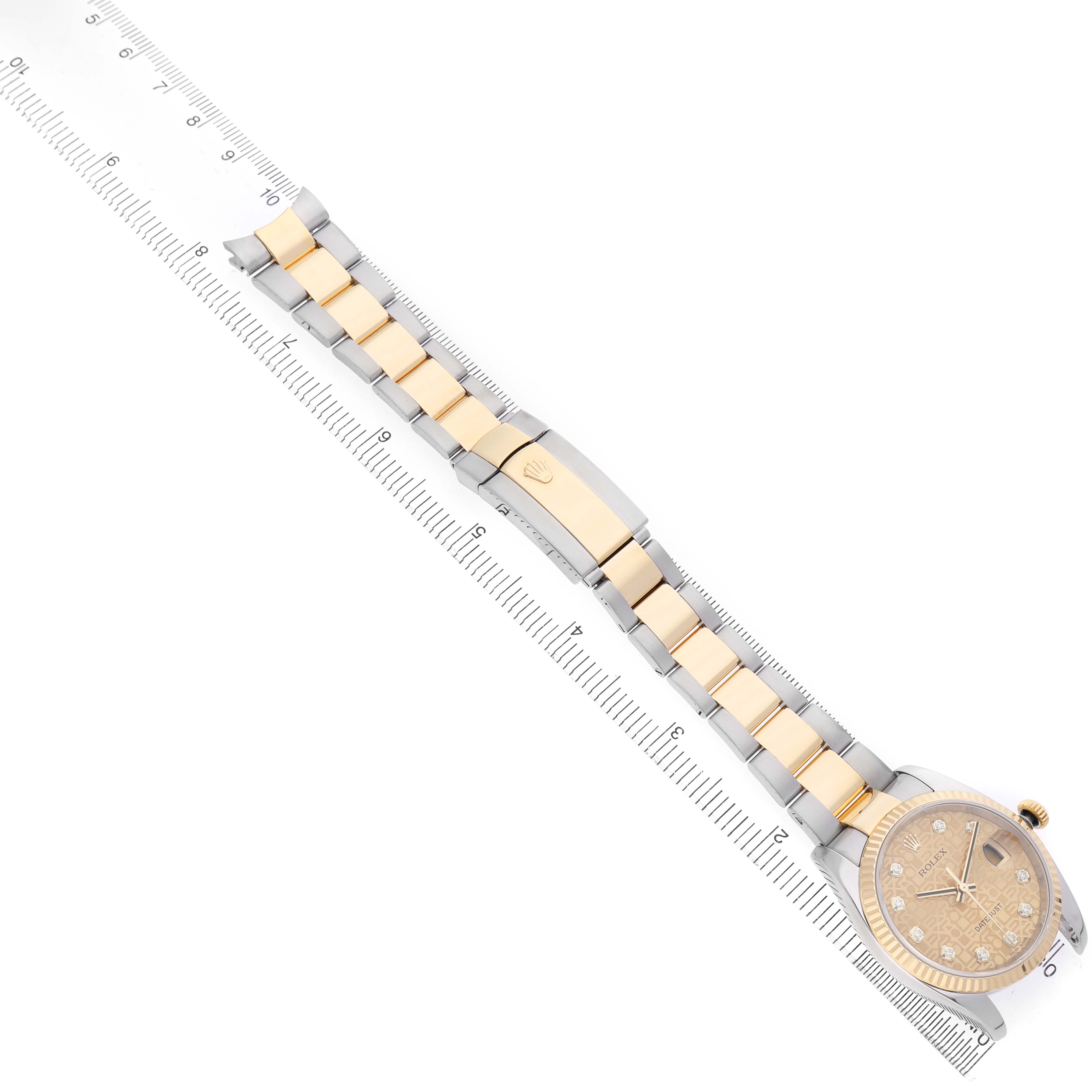 The Rolex Datejust 116233 Men's Stainless Steel Champagne Dial watch is shown from a top-down angle, displaying the full length of the bracelet and dial positioned on a ruler.