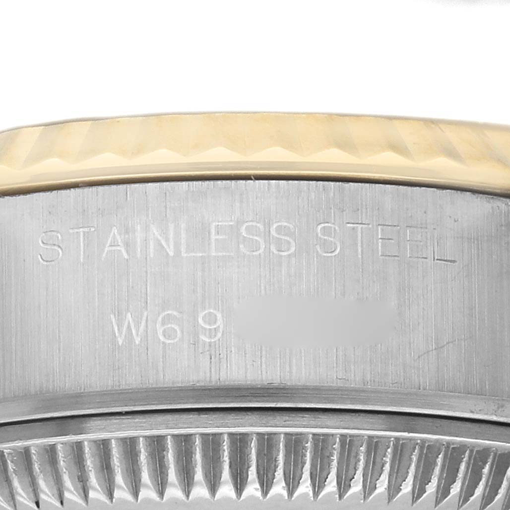 This image shows a close-up of the case side of a Rolex Datejust 69173 Women's Steel and Gold (two tone) Champagne Dial 69173 Women's Steel and Gold (two tone) Champagne Dial, displaying the fluted bezel and engravings indicating stainless steel.