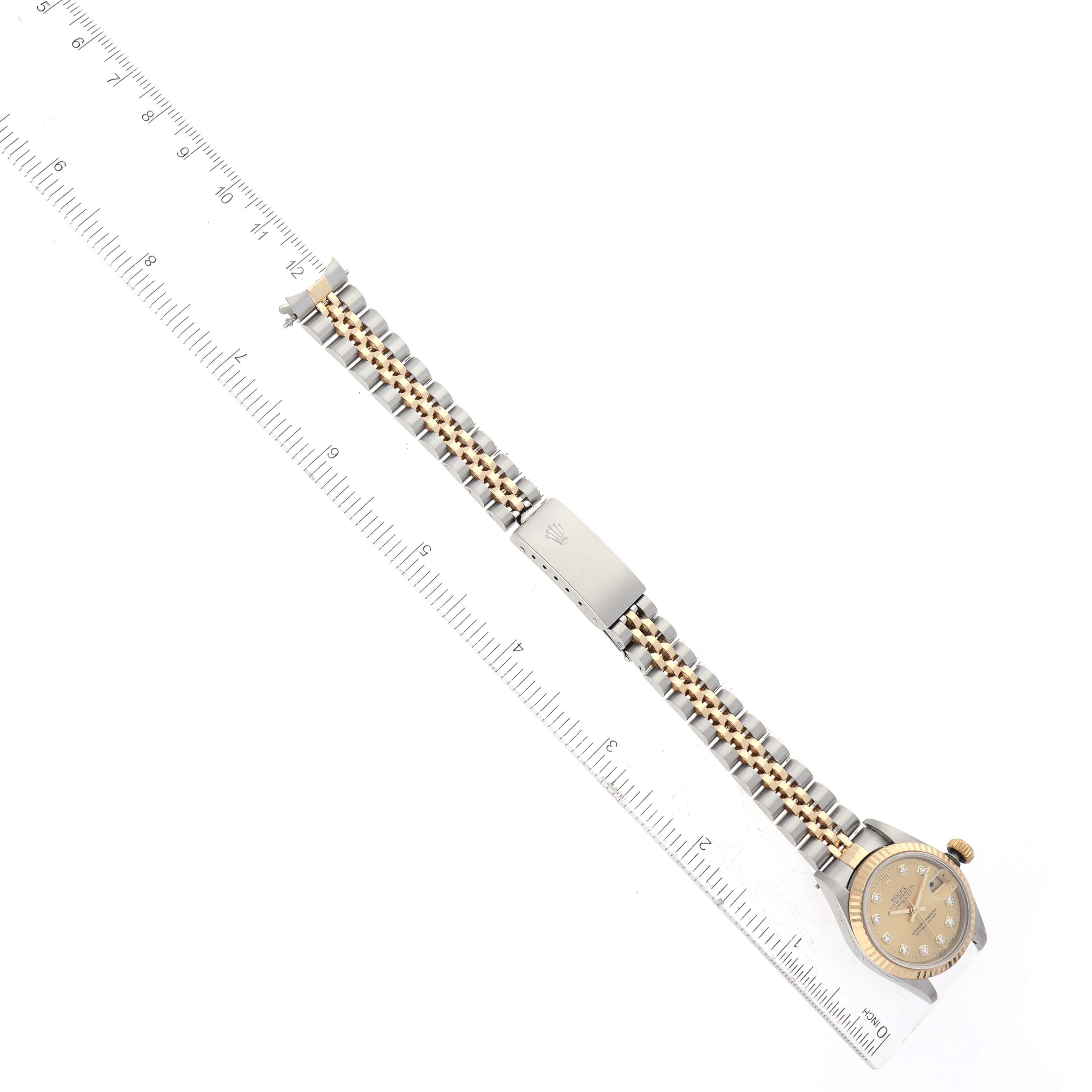 The image shows a top view of a Rolex Datejust 69173 Women's Steel and Gold (two tone) Champagne Dial 69173 Women's Steel and Gold (two tone) Champagne Dial watch, displaying its bracelet, clasp, and face next to a ruler for measurement.