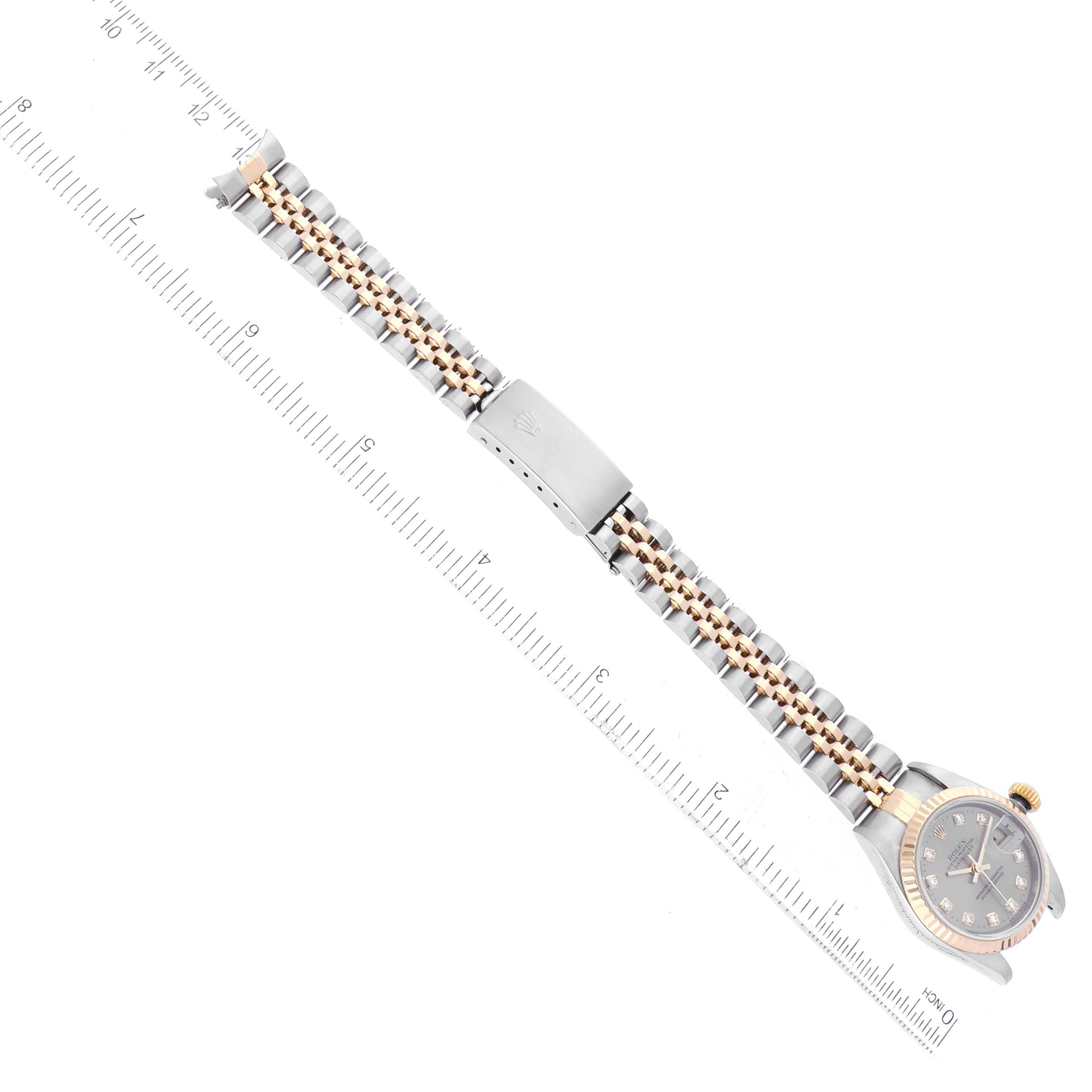 The image shows a top-down view of a Rolex Datejust 79173 Women's Steel and Gold (two tone) Grey Dial 79173 Women's Steel and Gold (two tone) Grey Dial watch, highlighting its face, clasp, and two-tone bracelet, with a ruler for scale.