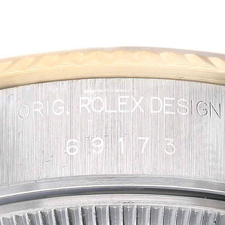 The image shows a close-up of the side engraving on a Rolex Datejust 69173 Women's Steel and Gold (two tone) White Dial watch, displaying the serial and design numbers.