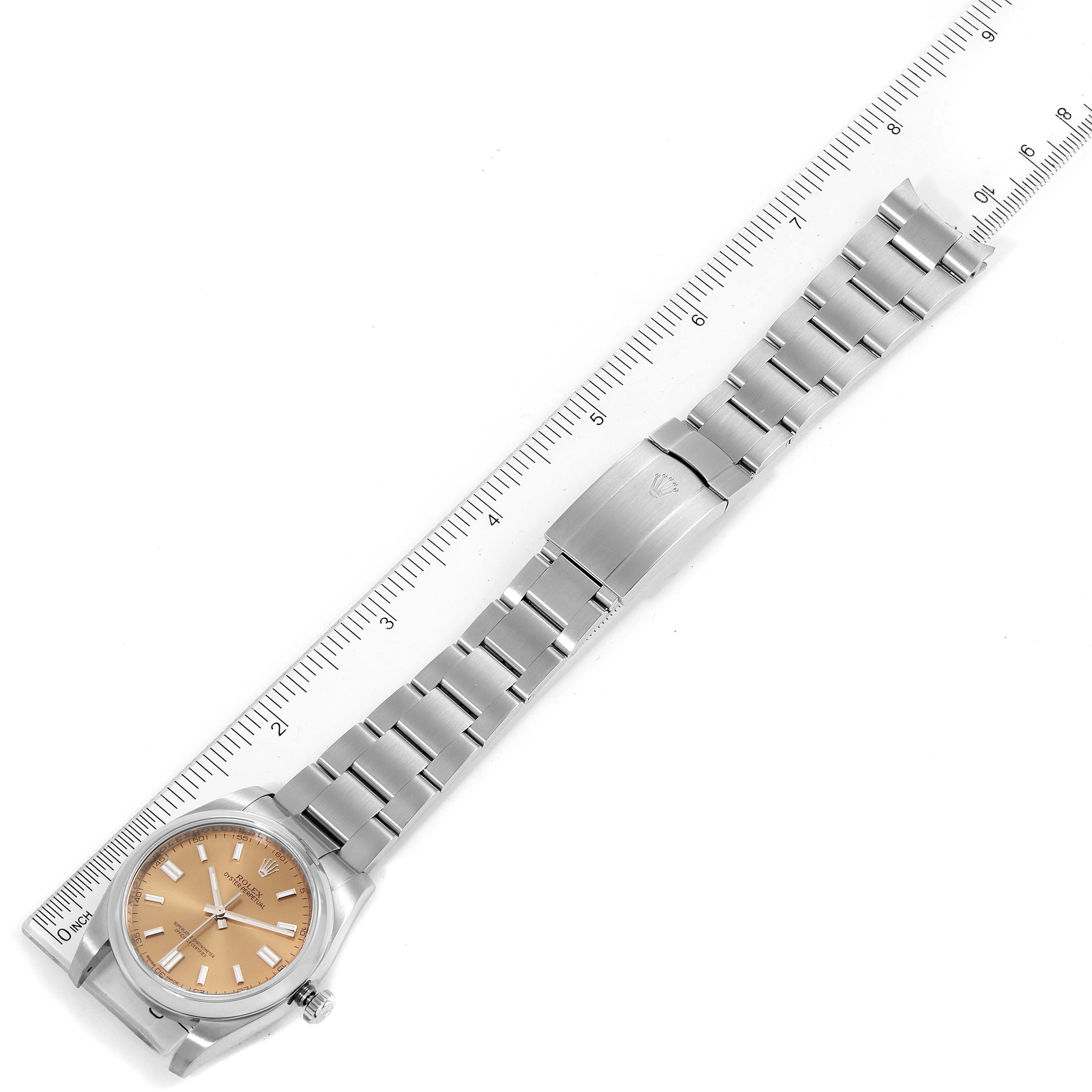 The image shows the entire length and dial of a Rolex Oyster Perpetual 116000 Men's Stainless Steel Champagne Dial 116000 Men's Stainless Steel Champagne Dial watch placed next to a ruler for sizing.