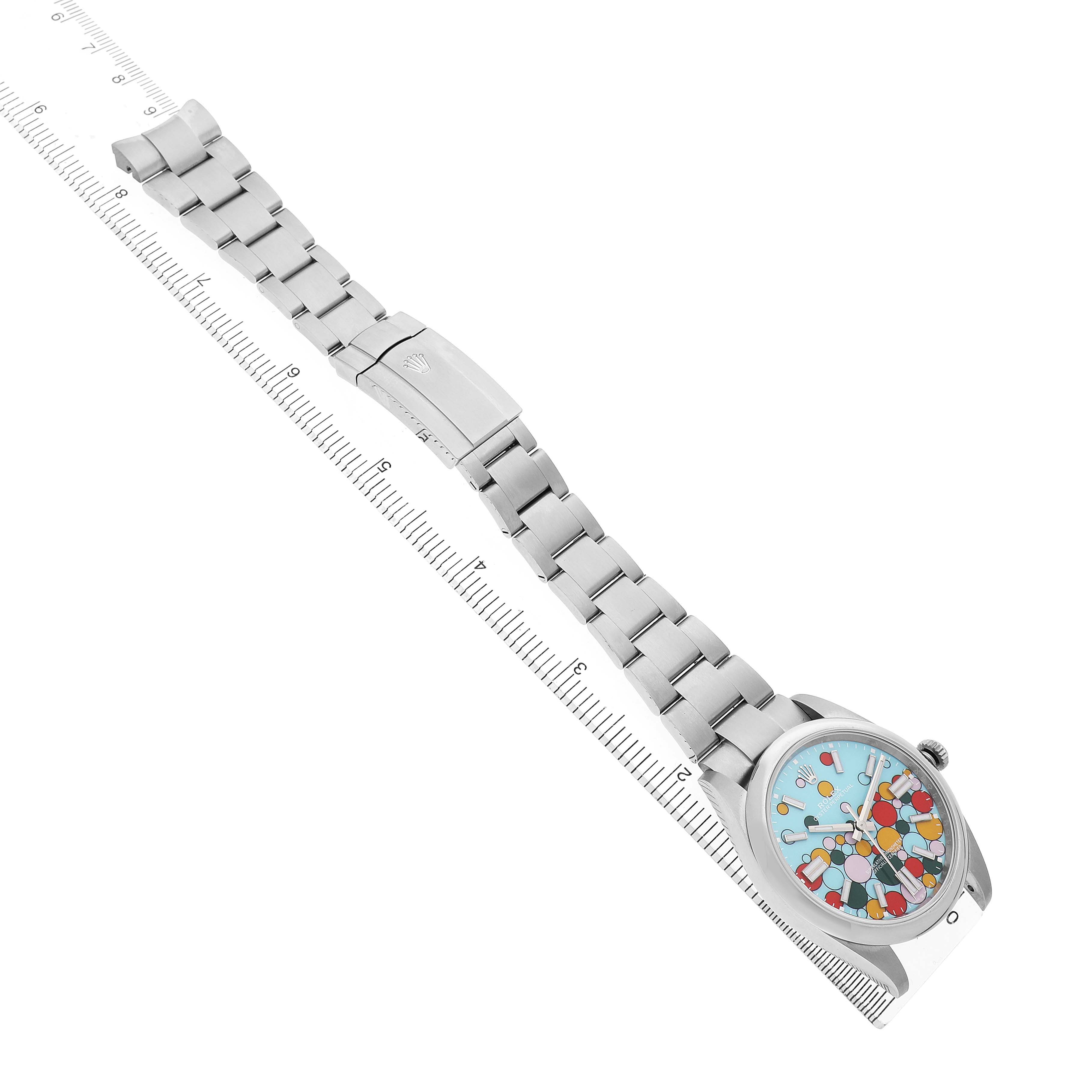 The Rolex Oyster Perpetual 124300 Men's Stainless Steel Blue Dial watch is displayed diagonally, showing the full bracelet, clasp, and colorful dial face.