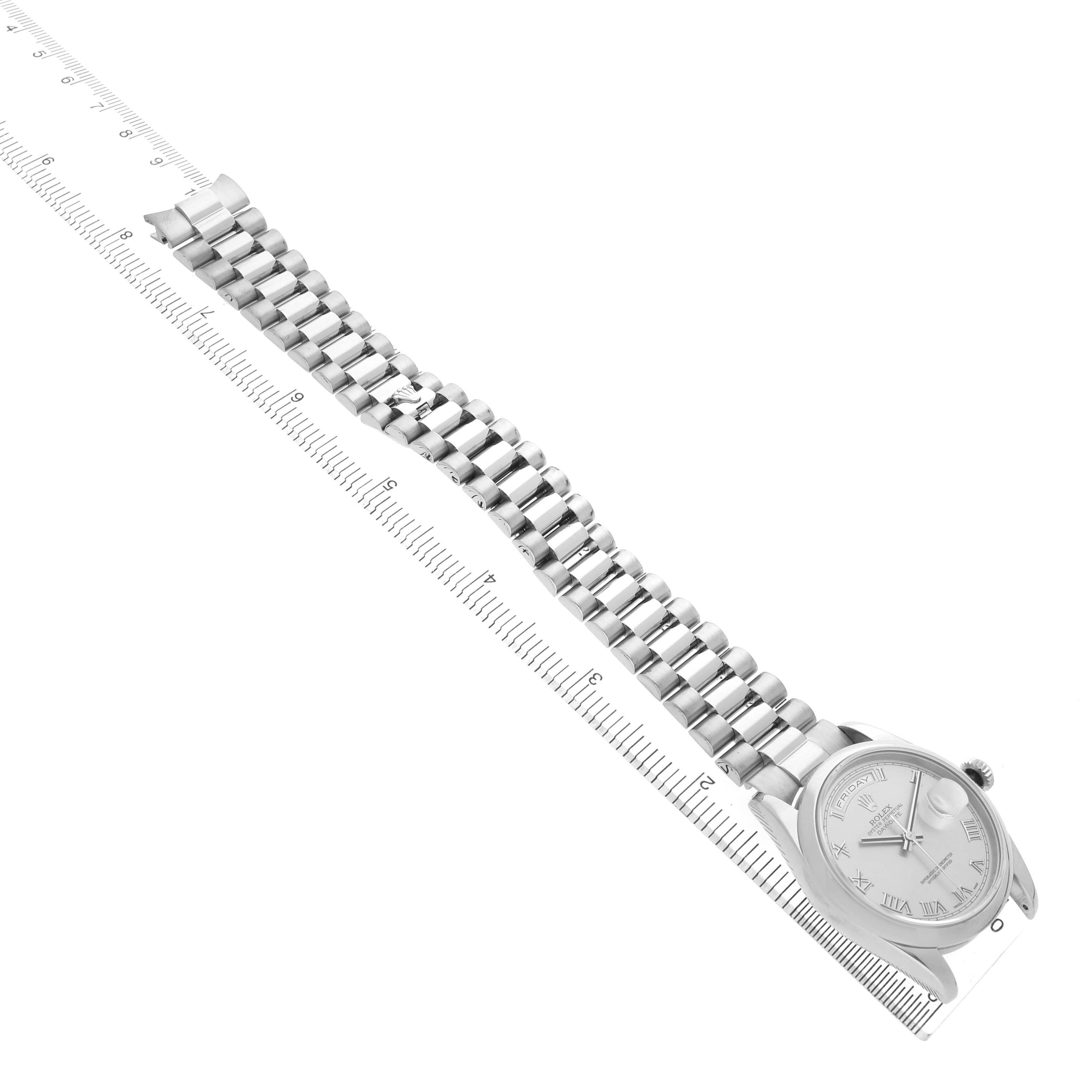The Rolex President 118209 Men's White Gold Silver Dial model watch is shown from an angled top view, displaying the dial, case, and full bracelet alongside a ruler.