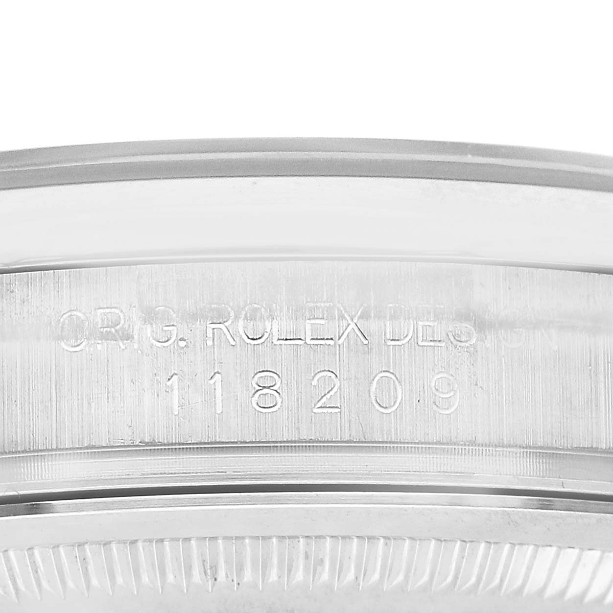 The image shows a close-up of the edge of a Rolex President 118209 Men's White Gold Silver Dial model, highlighting the engraved serial number and design details.