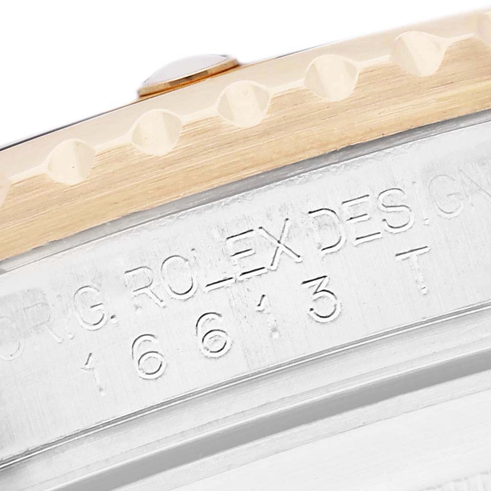 The image shows an angled close-up of the Rolex Submariner model 16613, featuring part of the bezel and engraved text on the case.