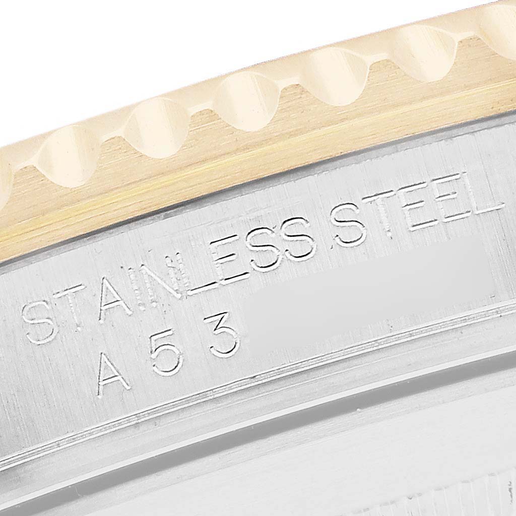 The image shows a close-up of the bezel and engraved details on the side of a Rolex Submariner model 16613, highlighting its stainless steel and gold accents.