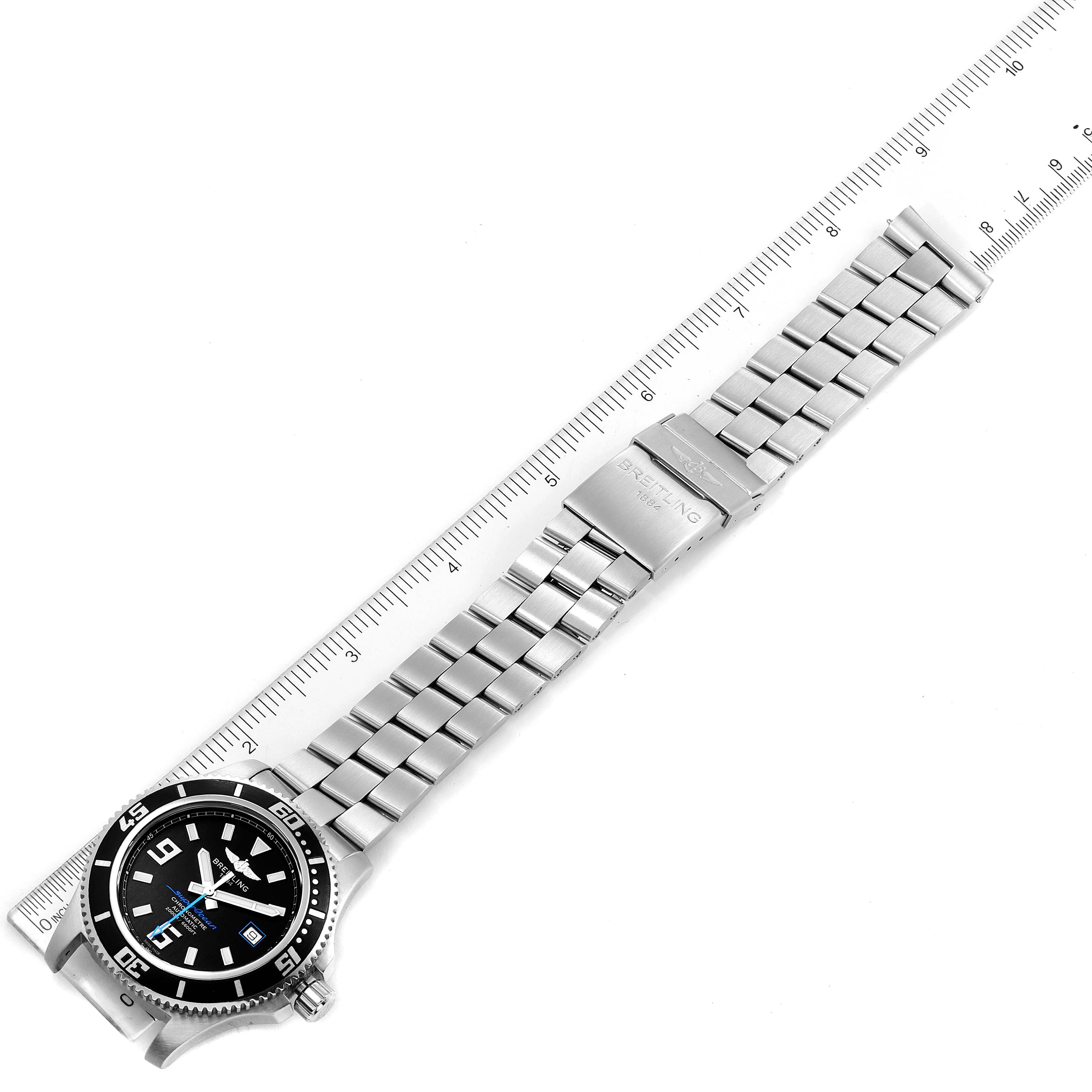 This image shows the Breitling Superocean A17391 Men
s Stainless Steel Black Dial A17391 Men
s Stainless Steel Black Dial watch laid flat, displaying its face, bezel, bracelet, and clasp next to a ruler.