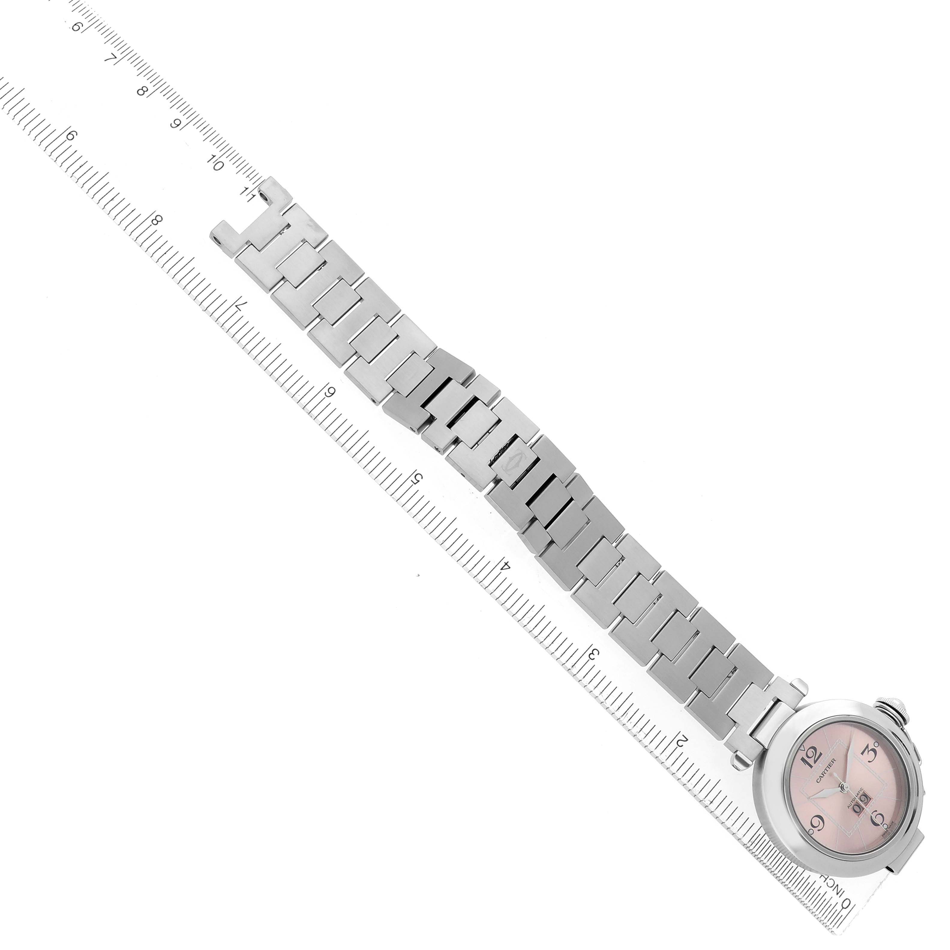 The Cartier Pasha model W31058M7 watch is shown at an overhead angle, displaying the face, full metal bracelet, and clasp beside a ruler for scale.