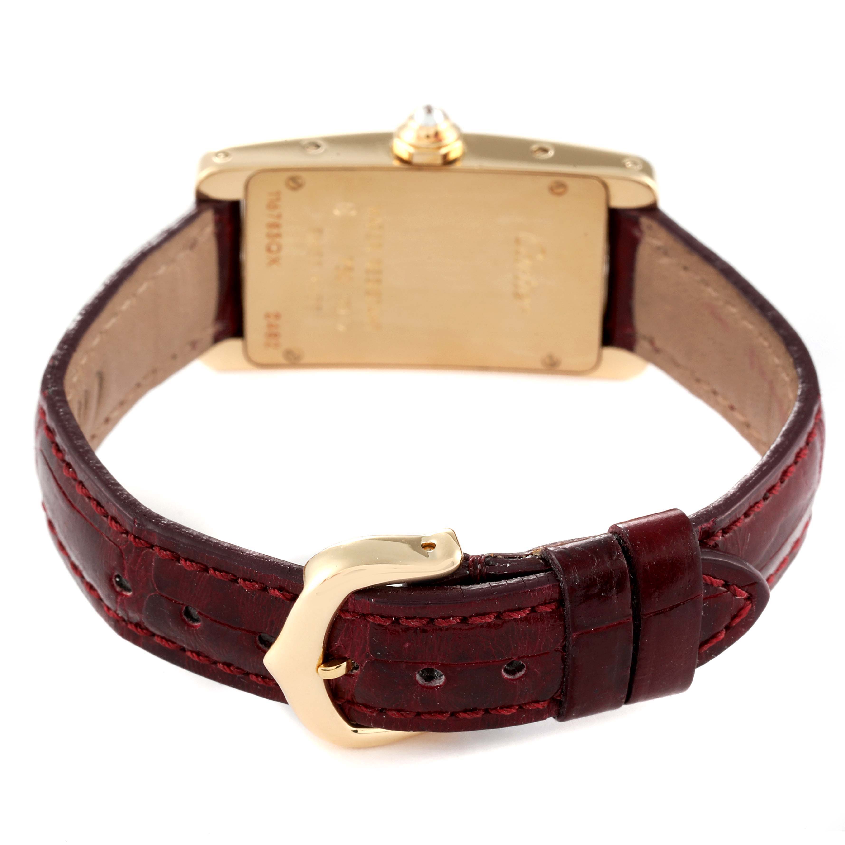 This image shows the back view of a Cartier Tank Américaine watch with its gold case and brown leather strap with a buckle.