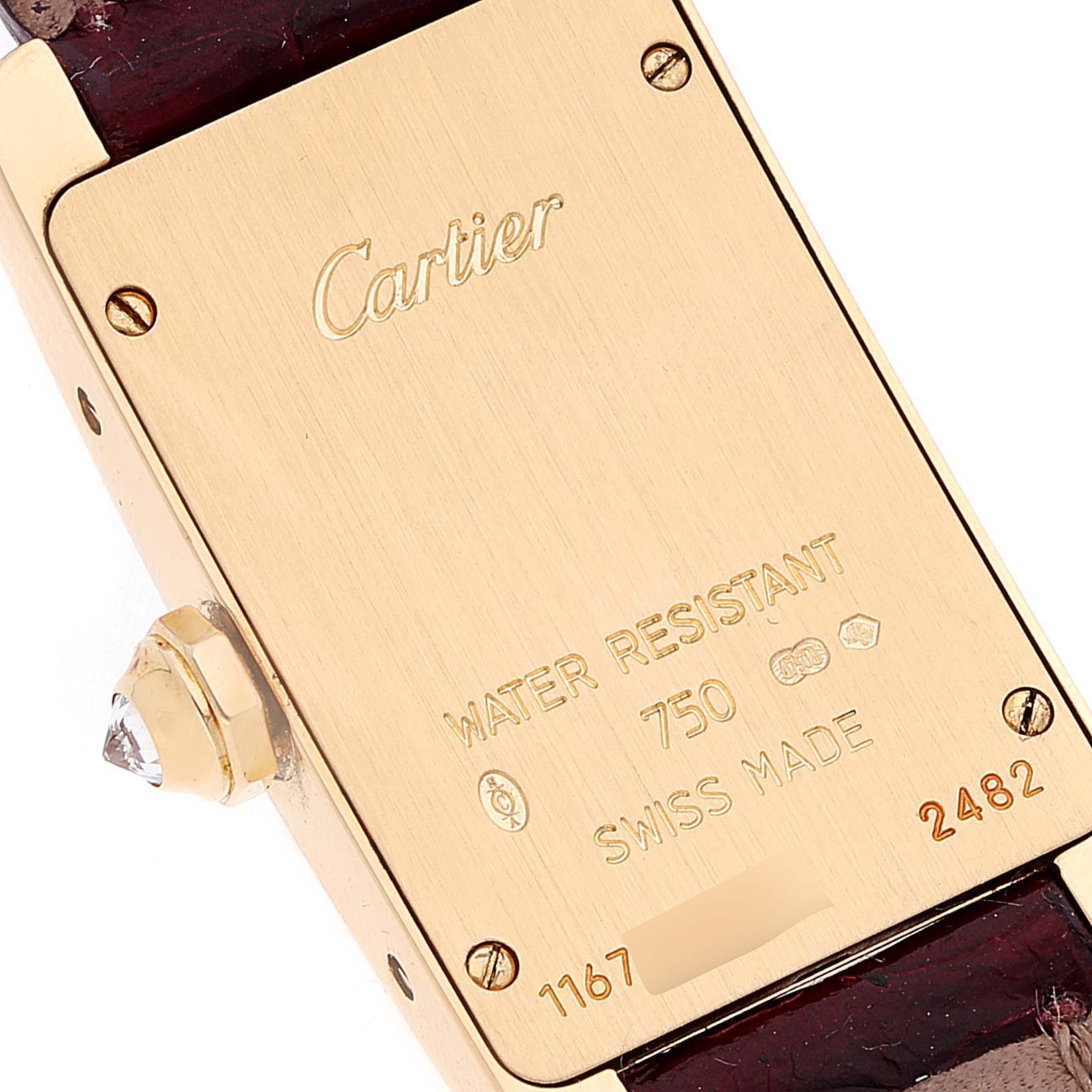This image shows the back of a Cartier Tank Americaine WB707231 Women's Yellow Gold Silver Dial WB707231 Women's Yellow Gold Silver Dial watch, highlighting the engravings and crown with a gemstone.