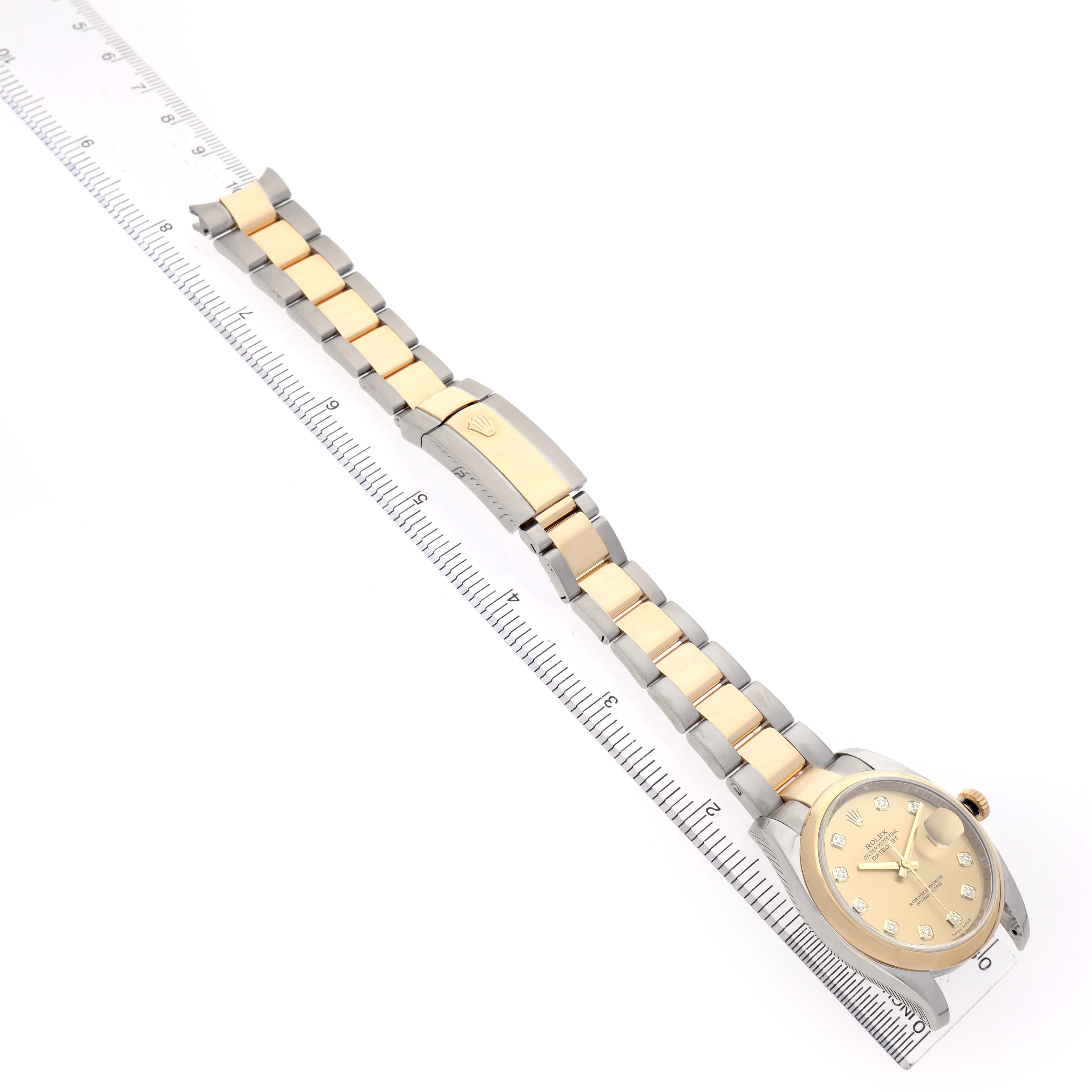 The Rolex Datejust 116203 Men's Steel and Gold (two tone) Champagne Dial watch is shown from a top-down angle highlighting the face, bracelet, and clasp alongside a ruler.