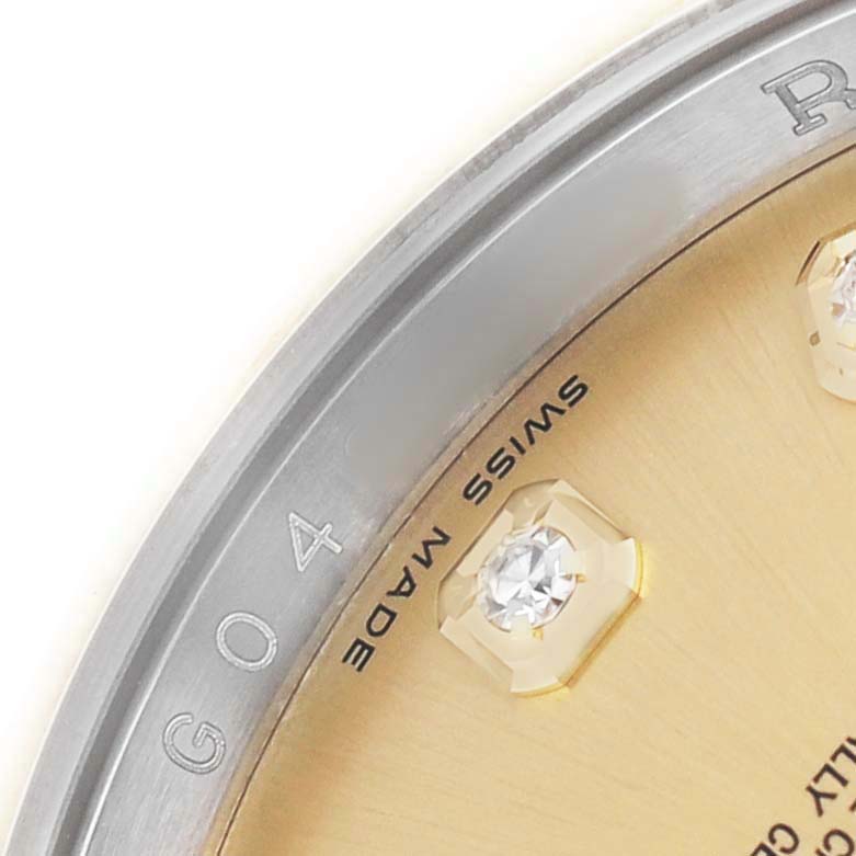 The image shows an angled close-up of a Rolex Datejust 116203 Men's Steel and Gold (two tone) Champagne Dial dial, featuring part of the rehaut with etched lettering and a diamond hour marker.