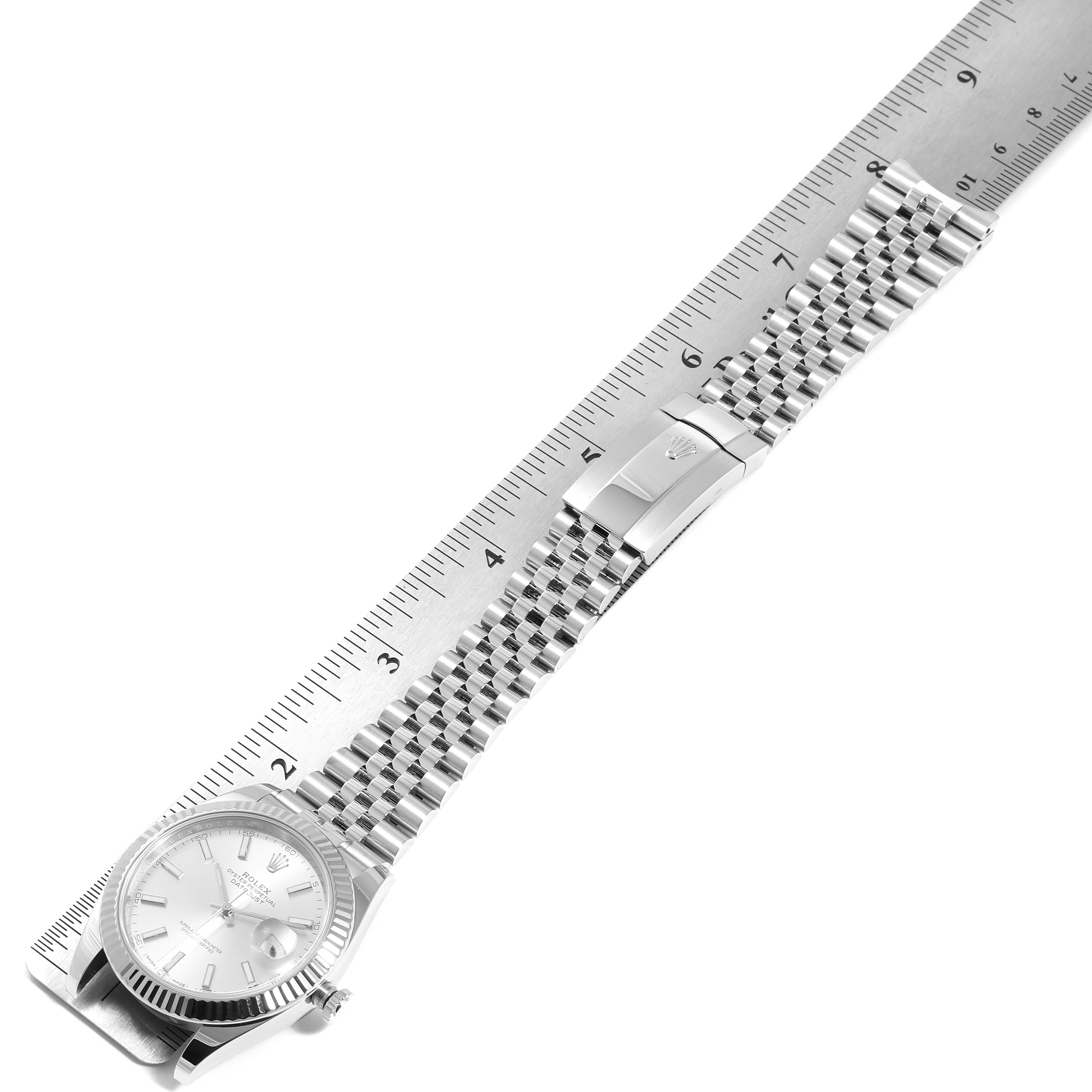 The Rolex Datejust 41 126334 Men's Stainless Steel Silver Dial 126334 Men's Stainless Steel Silver Dial watch is shown laid flat, displaying its silver dial, fluted bezel, Jubilee bracelet, clasp, and adjacent ruler.