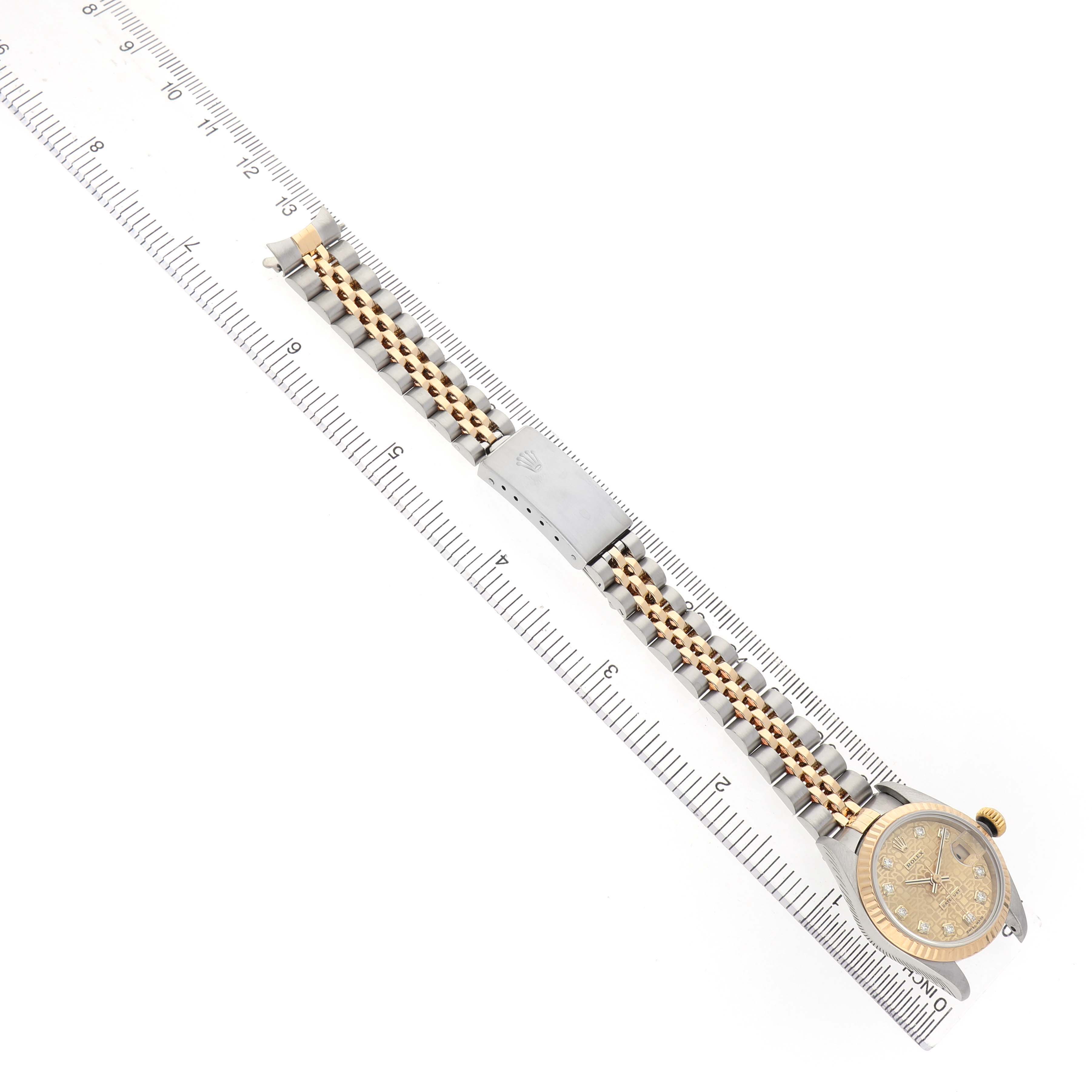 The Rolex Datejust 79173 Women's Stainless Steel Champagne Dial watch is shown from a top-down angle, displaying the full bracelet, clasp, and watch face alongside a ruler for scale.