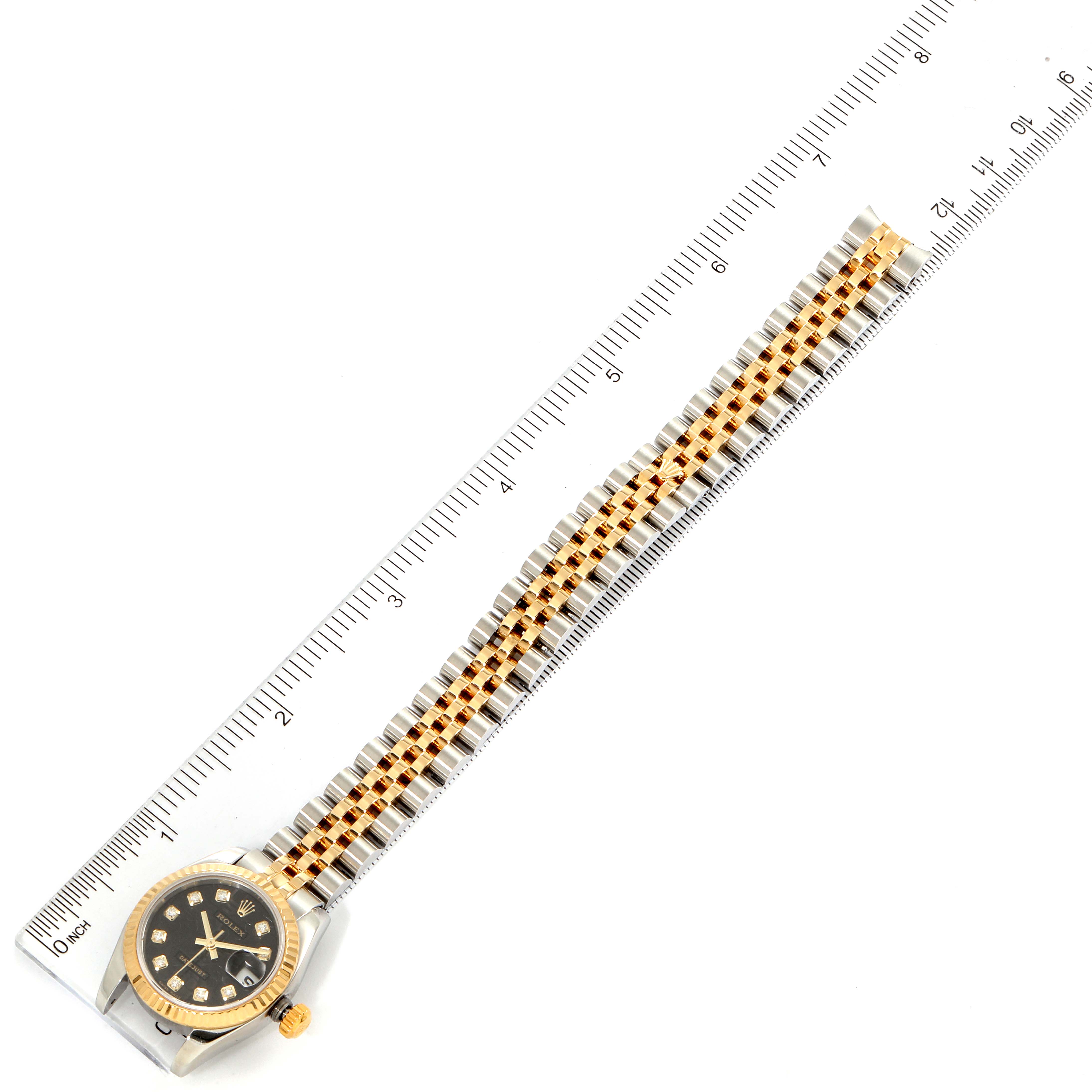 The Rolex Datejust 179173 Women's Steel and Gold (two tone) Black Dial 179173 Women's Steel and Gold (two tone) Black Dial watch is shown face-up, aligned with a ruler, displaying the dial, bezel, crown, and bracelet.
