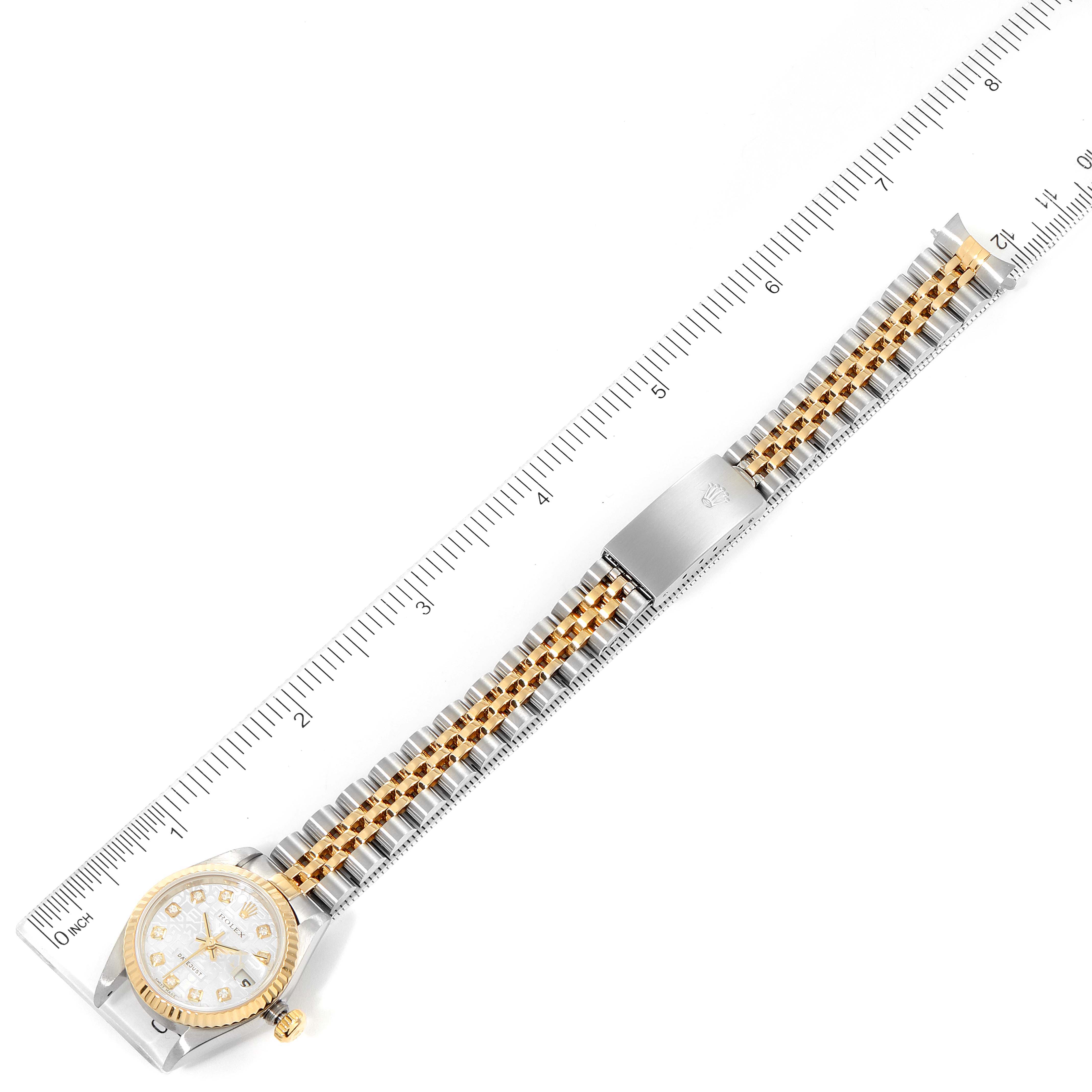 The image shows a top-down view of a Rolex Datejust 79173 Women
s Steel and Gold (two tone) Silver Dial 79173 Women
s Steel and Gold (two tone) Silver Dial watch with a two-tone bracelet and a ruler for scale.