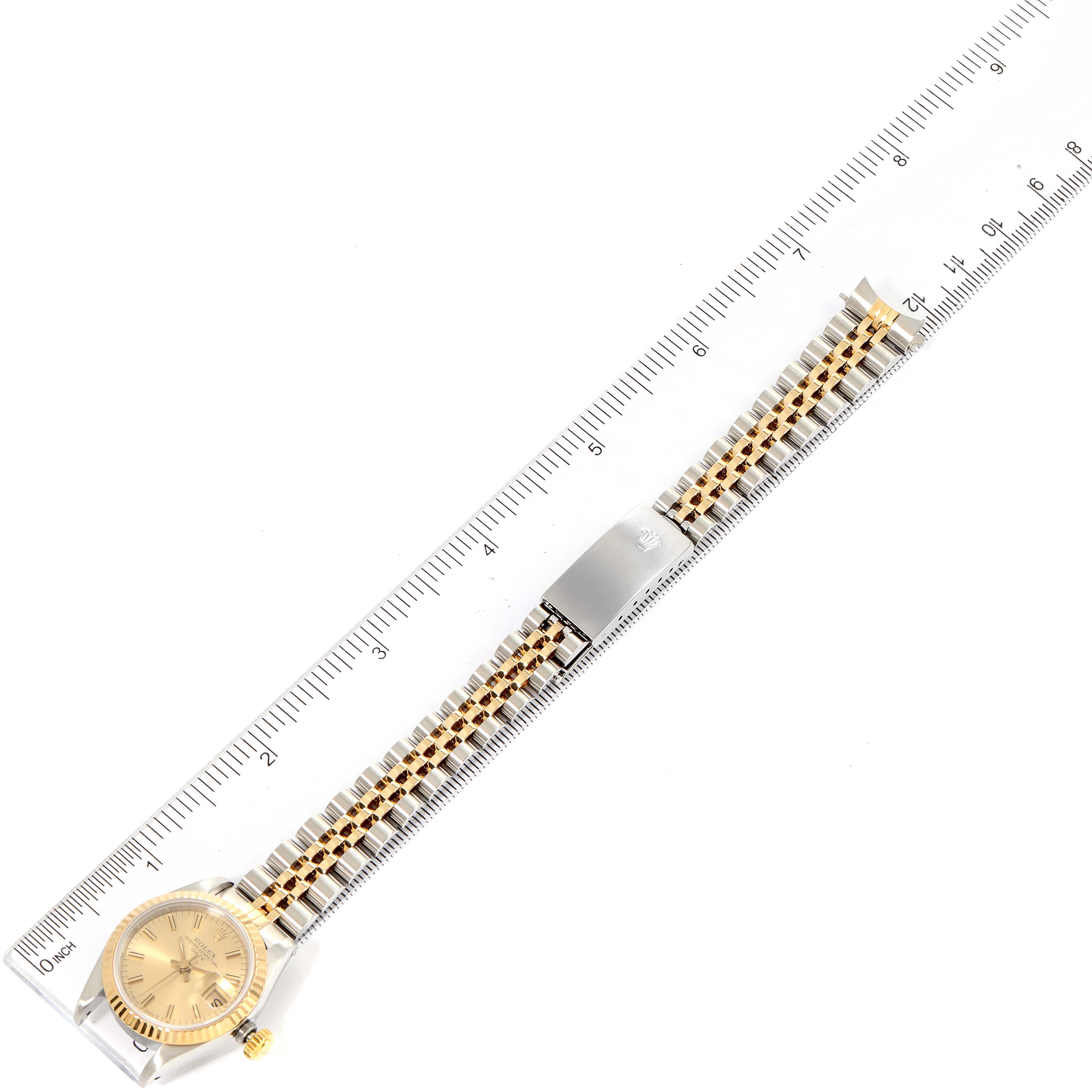 This image shows a Rolex Datejust 69173 Women
s Steel and Gold (two tone) Champagne Dial 69173 Women
s Steel and Gold (two tone) Champagne Dial watch with a gold dial and a two-tone bracelet, photographed alongside a ruler.