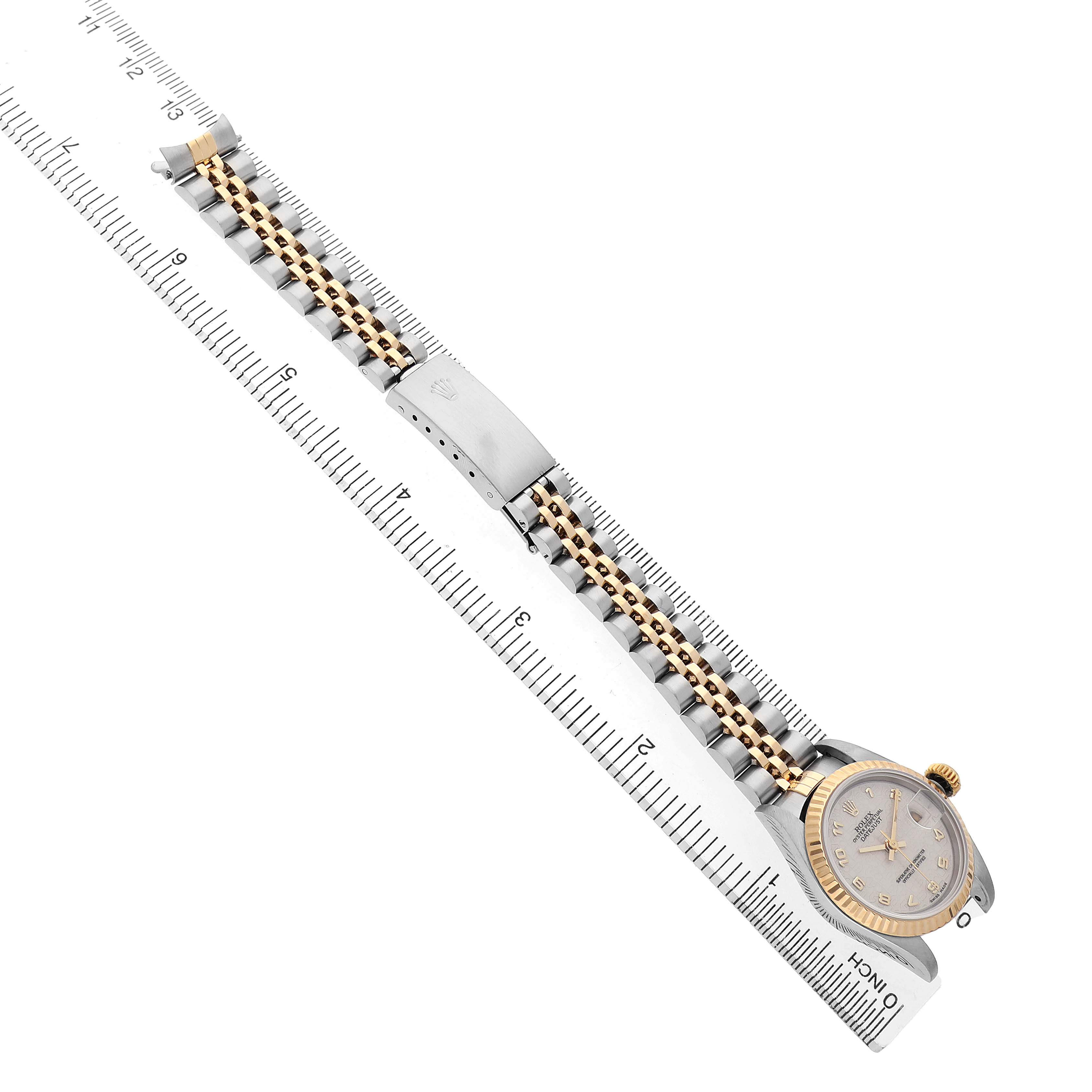 The image shows a Rolex Datejust 79173 Women's Steel and Gold (two tone) White Dial watch laid flat with a focus on its bracelet and clasp, aligned diagonally on a ruler.
