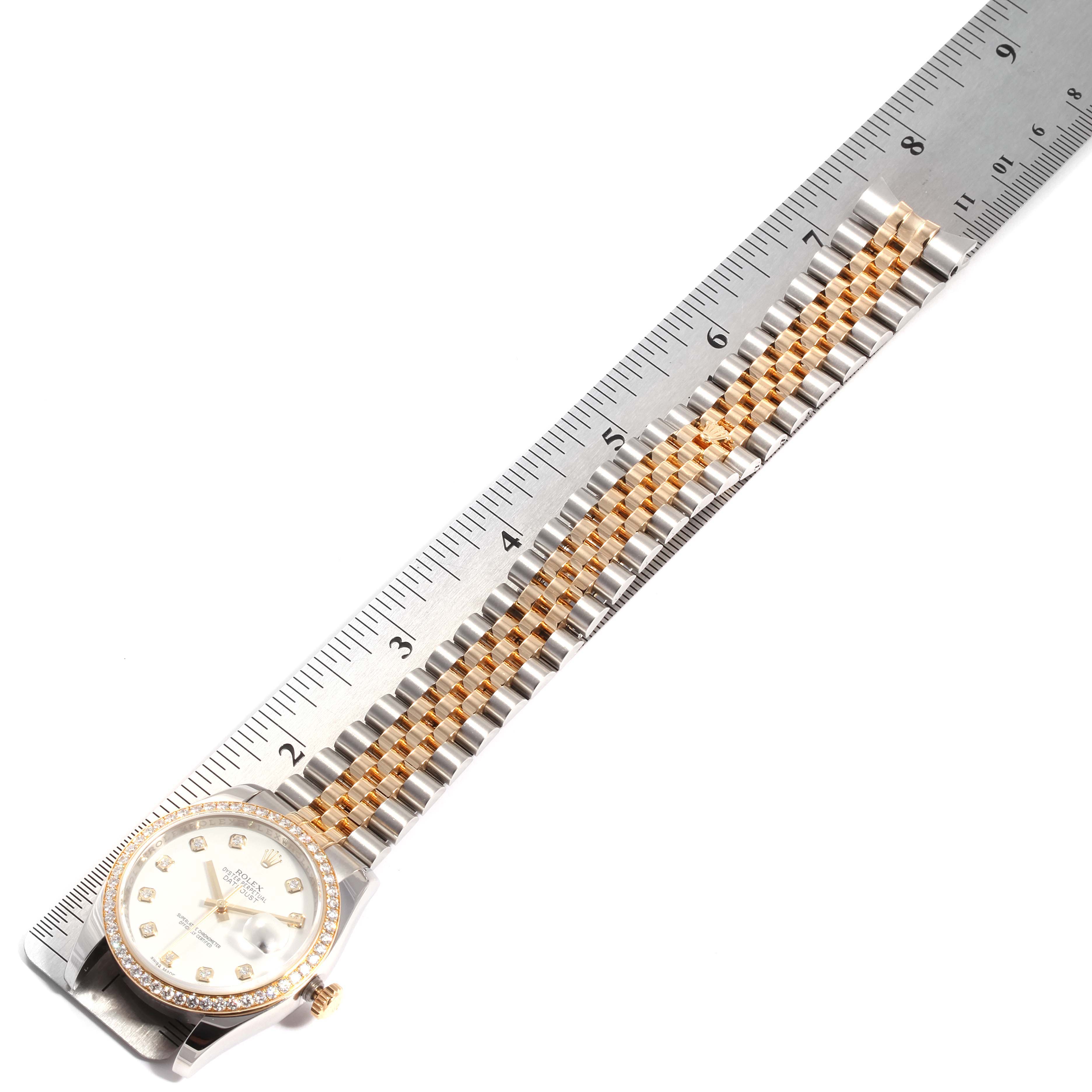 The image shows a Rolex Datejust 116243 Men's Steel and Gold (two tone) White Dial 116243 Men's Steel and Gold (two tone) White Dial watch placed flat, with its bracelet and dial aligned with a ruler.