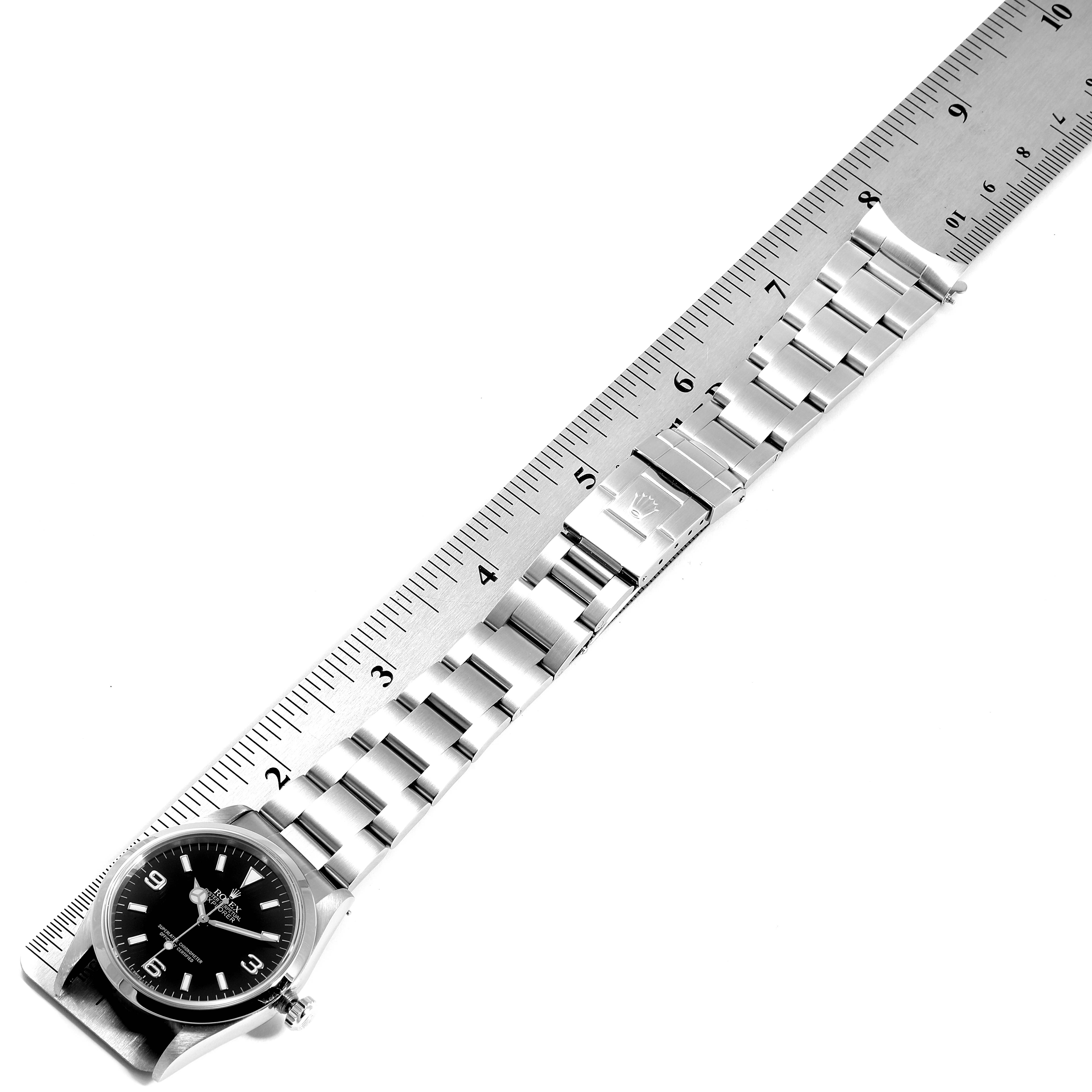 The Rolex Explorer 14270 Men
s Stainless Steel Black Dial 14270 Men
s Stainless Steel Black Dial watch is displayed flat with the dial, bracelet, and clasp visible, alongside a measuring ruler.