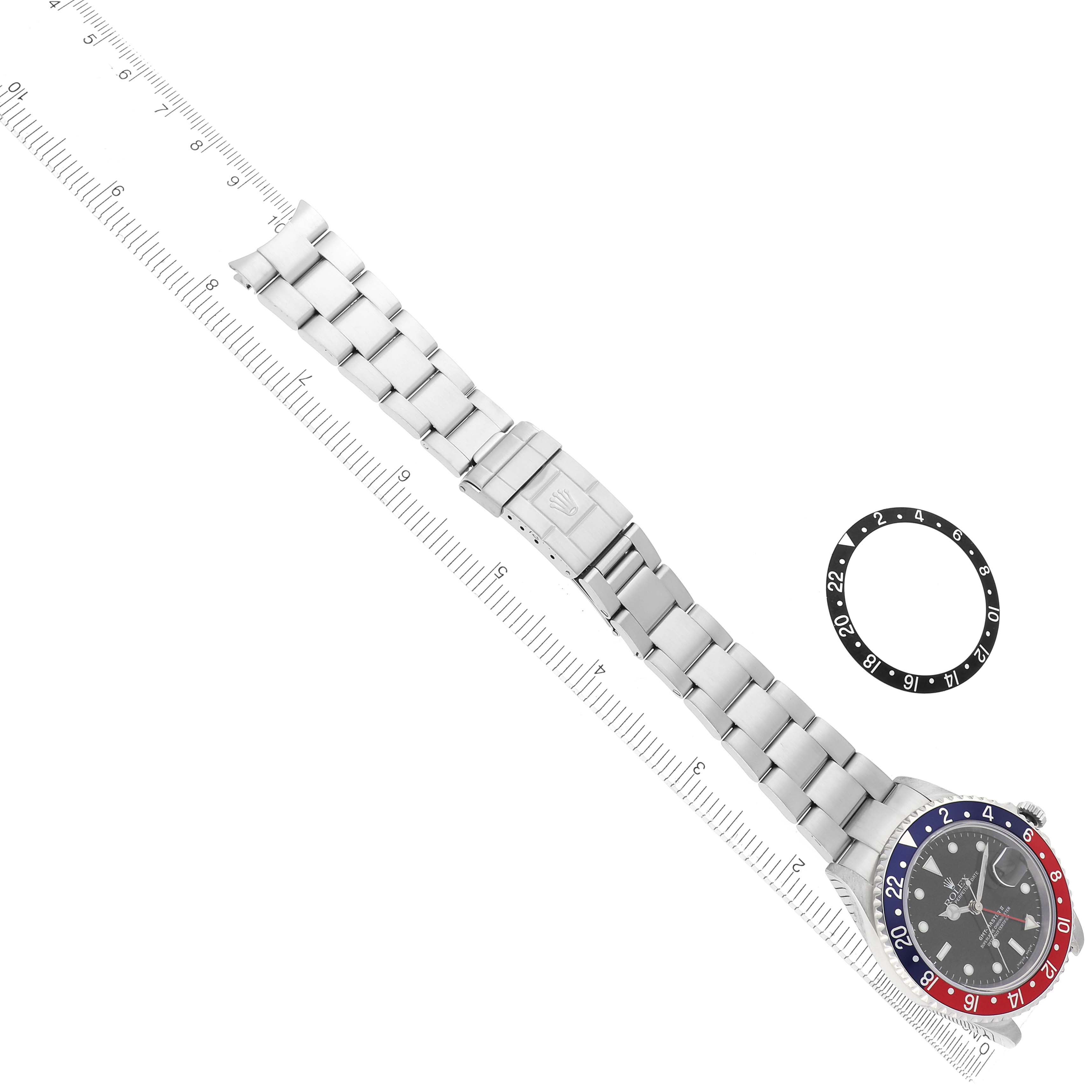 The image shows a Rolex GMT-Master model 16710 watch at a top-down angle with its bracelet extended alongside a bezel insert accessory.