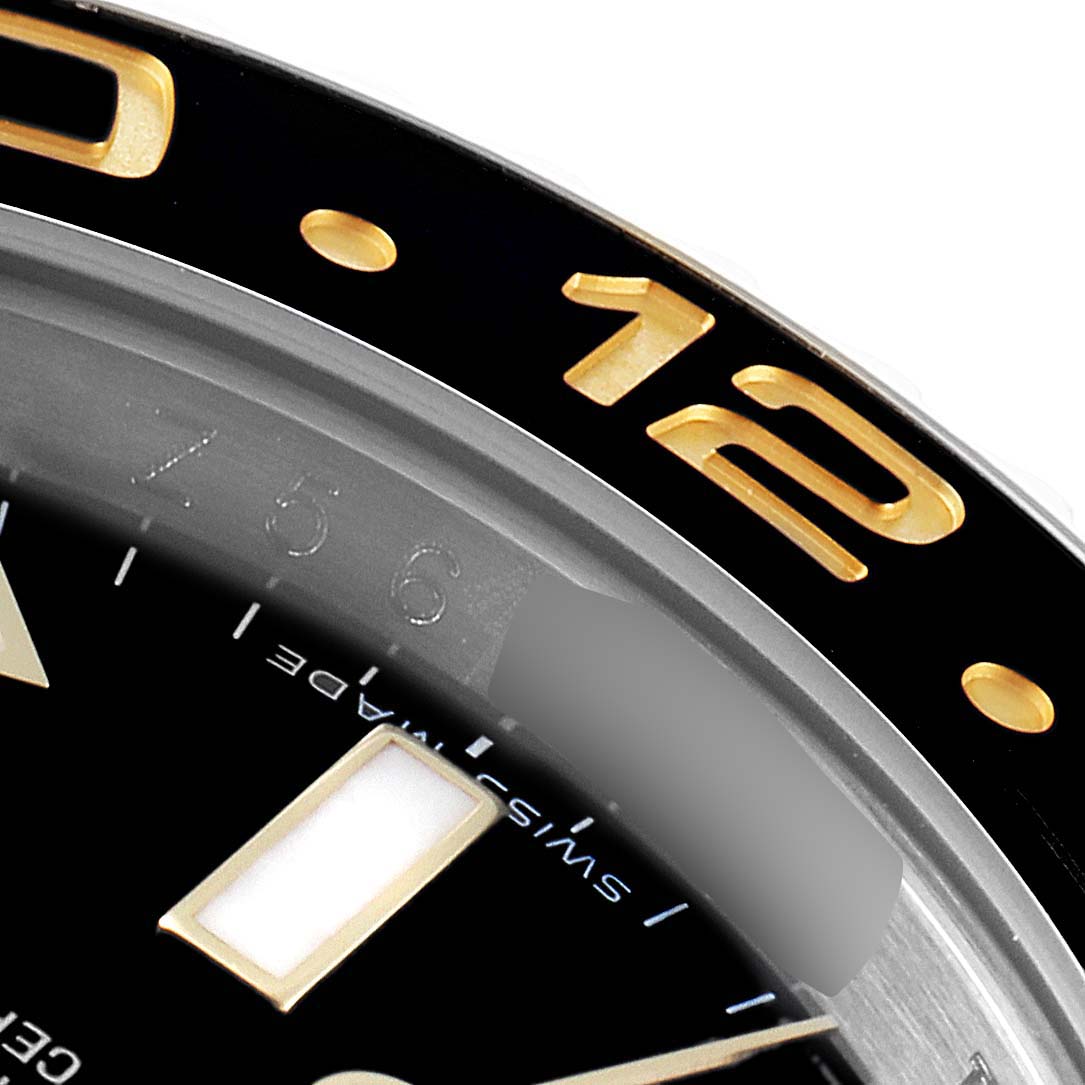 This image shows a close-up angle of the bezel and part of the dial of a Rolex GMT-Master 116713 Men's Steel and Gold (two tone) Black Dial 116713 Men's Steel and Gold (two tone) Black Dial watch.