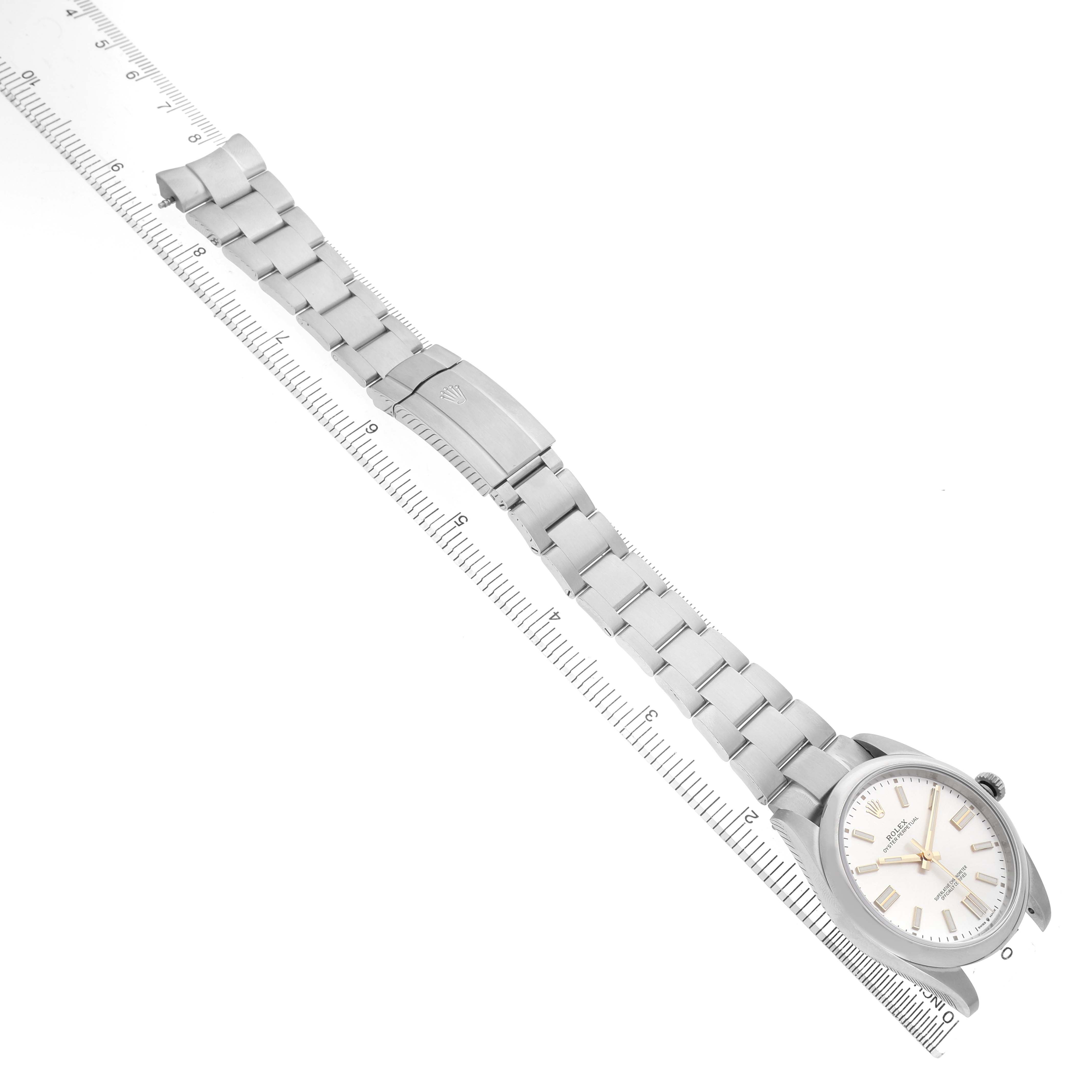 The Rolex Oyster Perpetual 124300 Men's Stainless Steel Silver Dial watch is shown from a top view, highlighting the dial, bracelet, and clasp against a ruler.