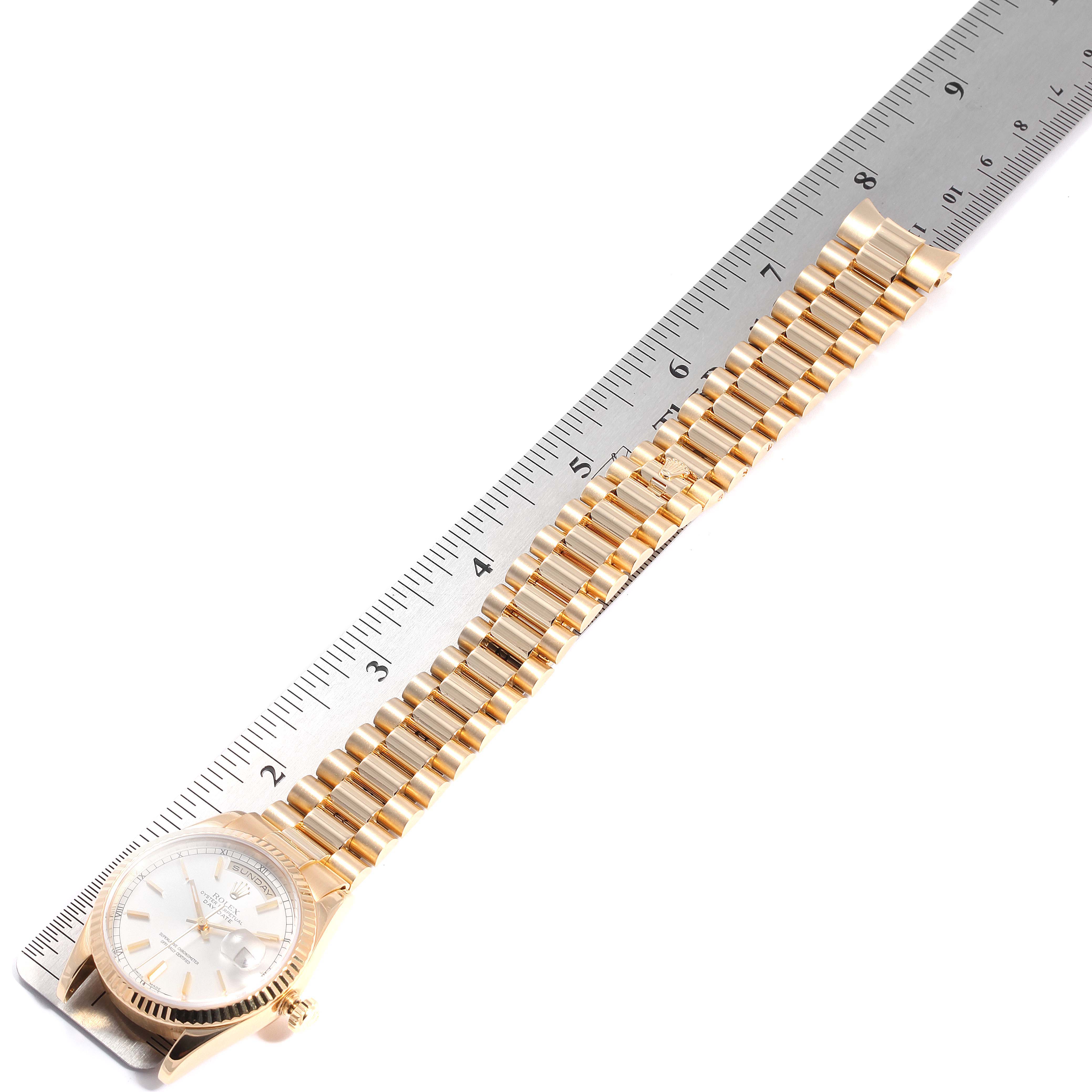 The image shows a Rolex President 118238 Men
s Yellow Gold Silver Dial 118238 Men
s Yellow Gold Silver Dial model watch, displayed laid flat next to a ruler, highlighting its bracelet and case.