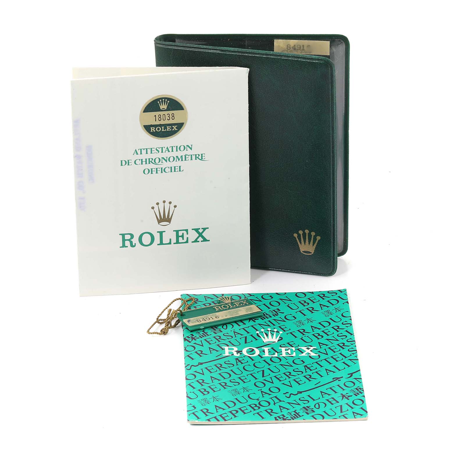The image shows the documentation and accessories for a Rolex President 18038 Men
s Yellow Gold Champagne Dial 18038 Men
s Yellow Gold Champagne Dial model watch, including booklets, a green wallet, and a tag.