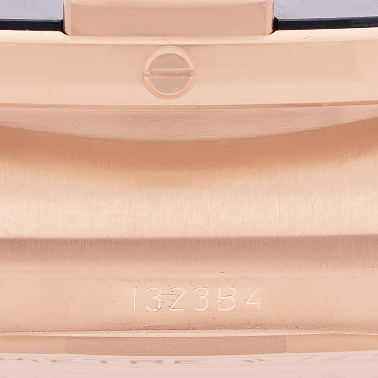 This close-up image shows the side of a Breitling Chronomat RB0136 Men's Rose Gold Blue Dial RB0136 Men's Rose Gold Blue Dial watch case with engraving and mechanical detailing visible.