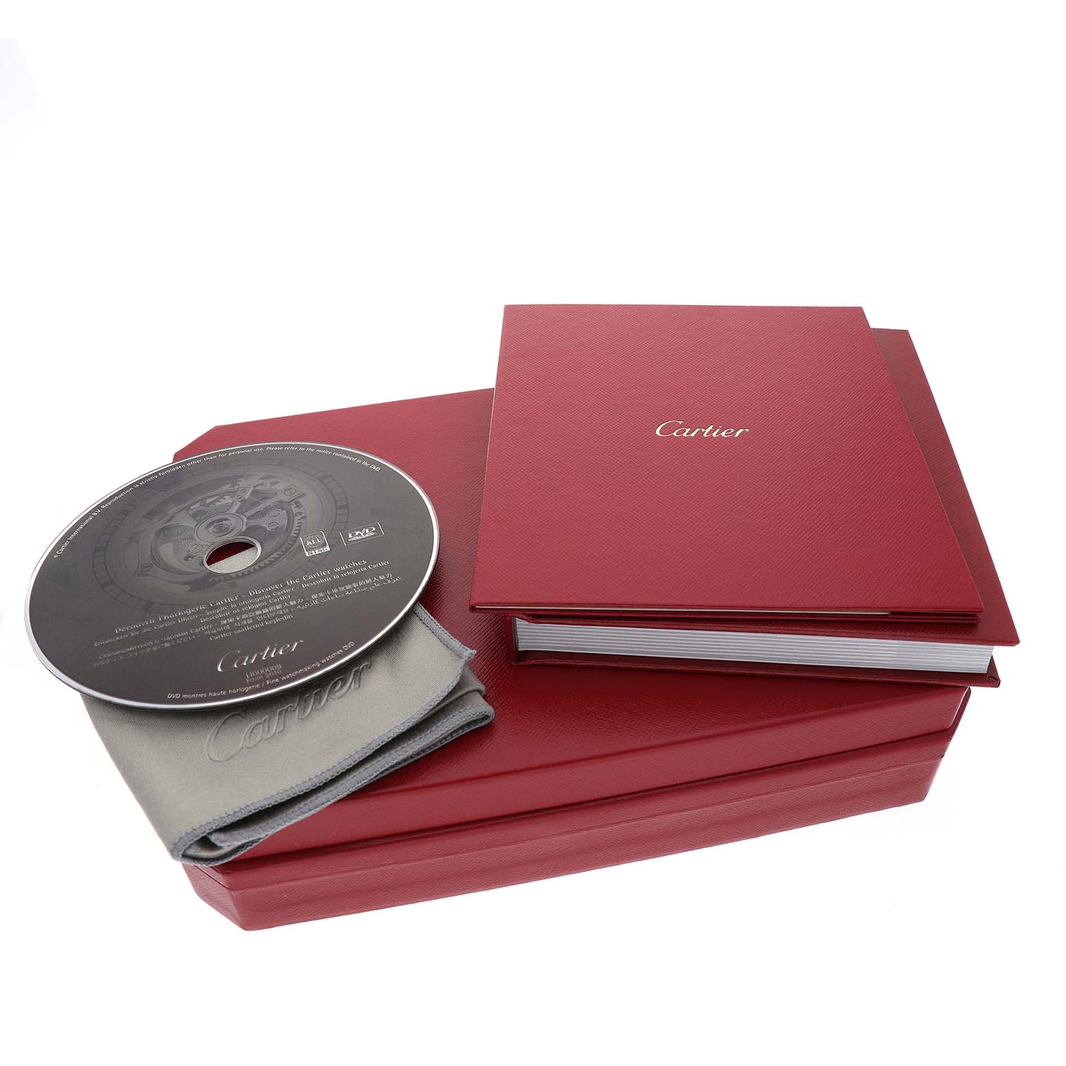 The image shows accessories for the Rotonde by Cartier, including a case, booklet, CD, and a cloth.