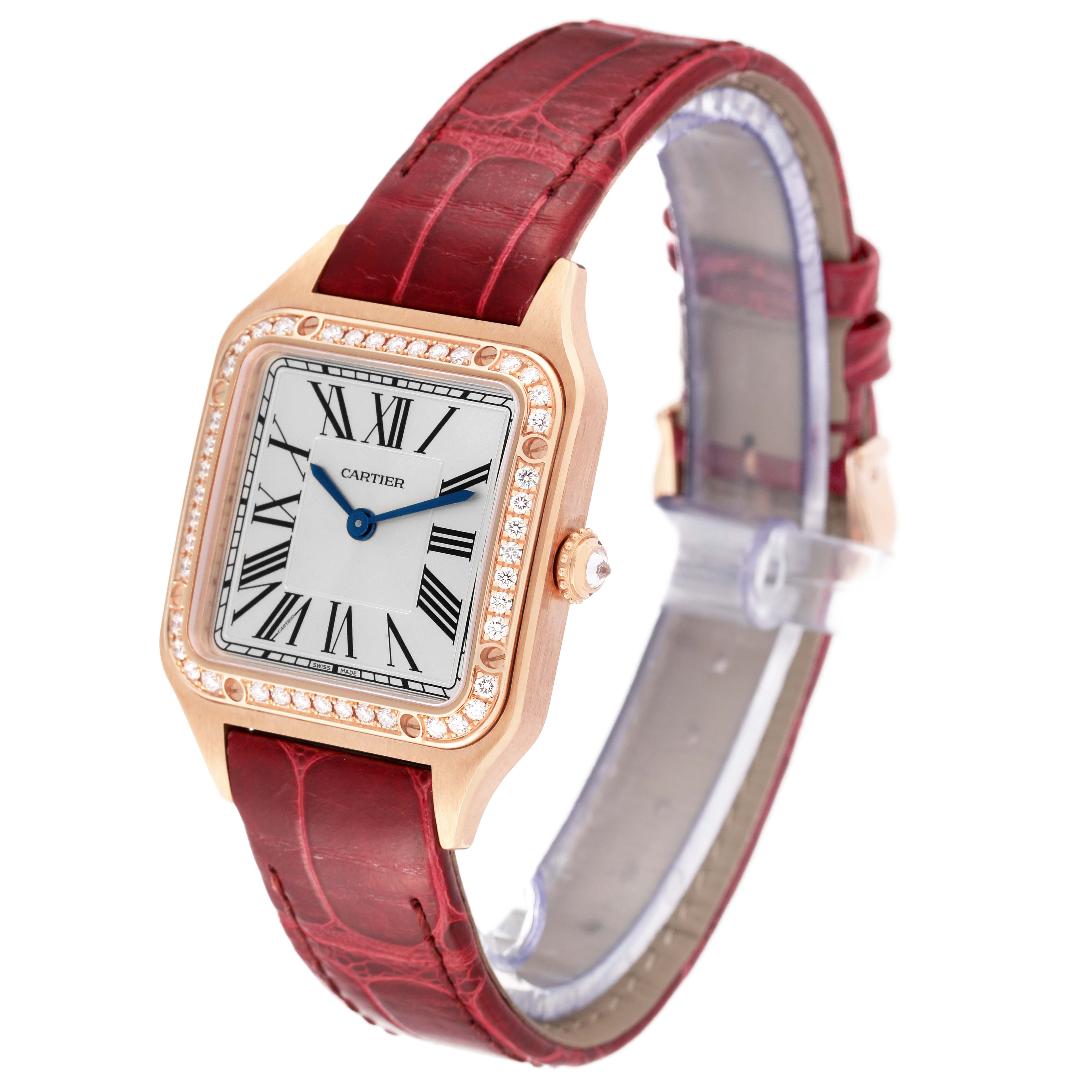 The Cartier Santos WJSA0017 Women's Rose Gold Silver Dial WJSA0017 Women's Rose Gold Silver Dial watch is shown at an angle displaying its face, bezel, crown, and red leather strap.
