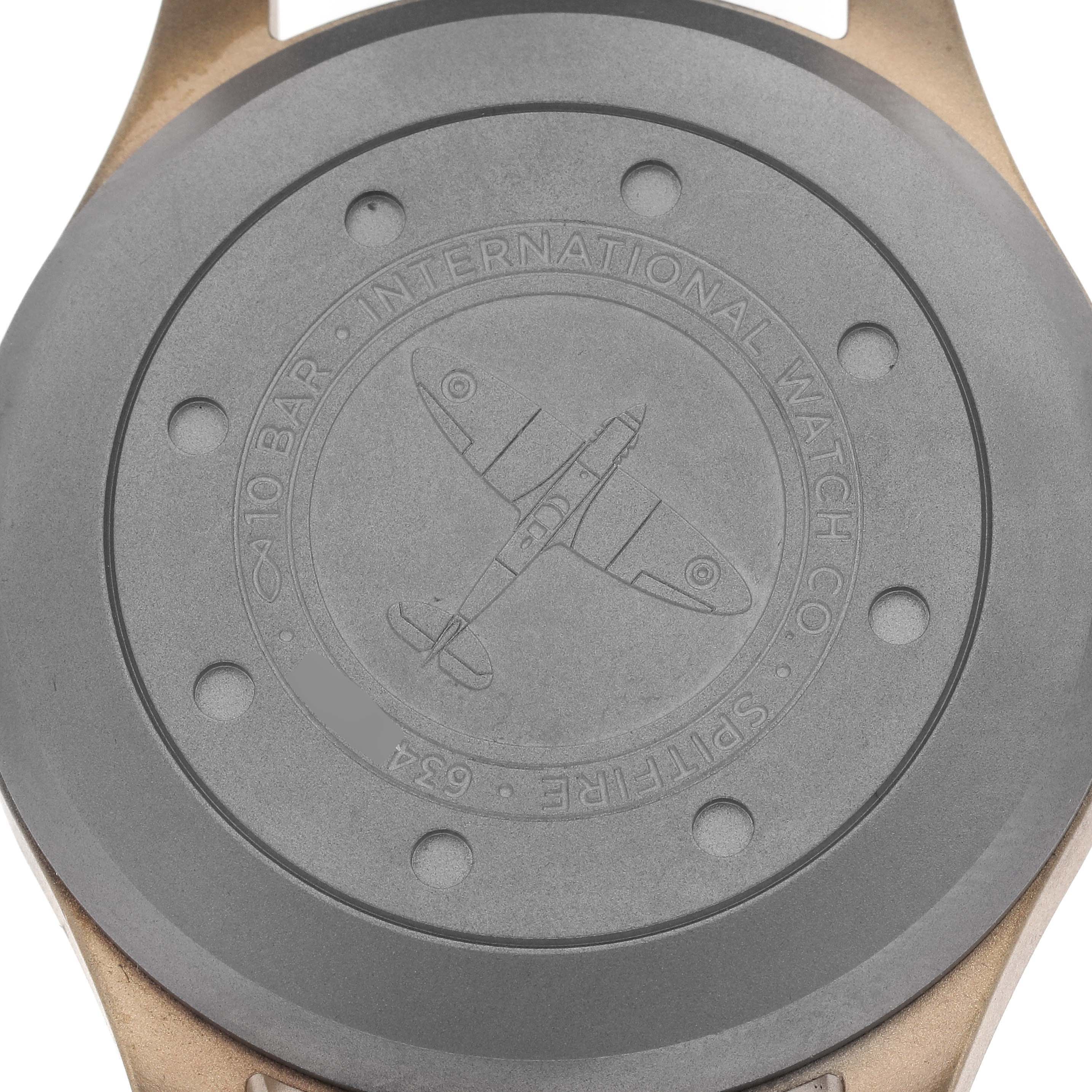 The image shows the case back of the IWC Pilot Men's watch, model number IW329702, featuring an engraved airplane and branding details.