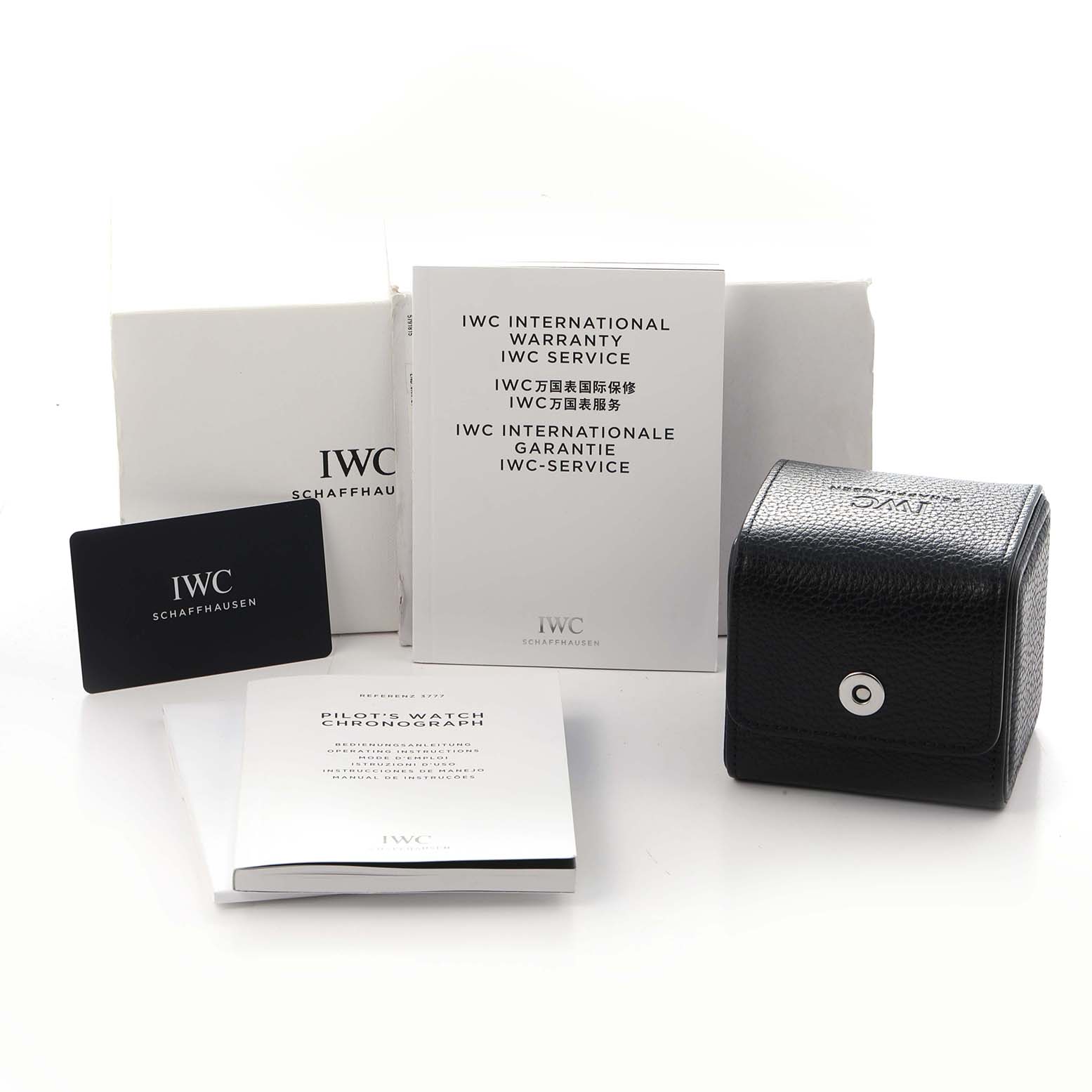 The image shows IWC Pilot model IW377710 watch accessories, including a black case, warranty card, manuals, and service documents, angled from the front.